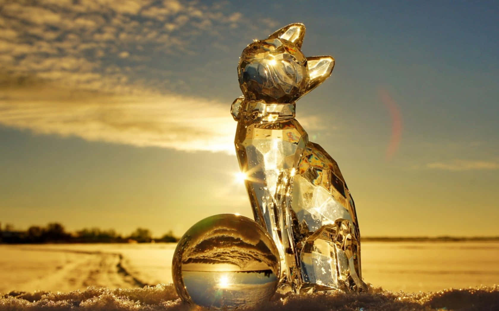 Ice Sculpture 桌布 壁紙 — 水晶貓雕像與球體在雪地上閃耀著金色夕陽的光芒，並帶有鏡頭光暈。