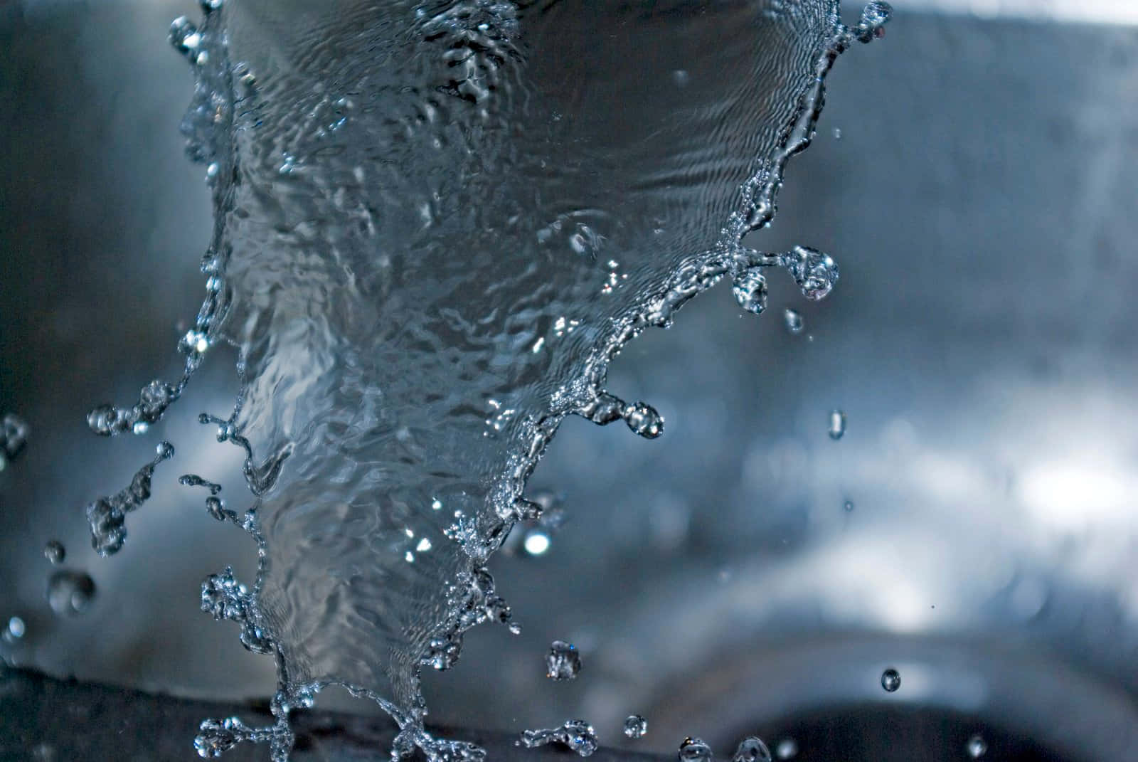 Splash 桌布 壁紙 — 水滴在模糊灰色背景上捕捉光線向上飛濺的動態特寫。