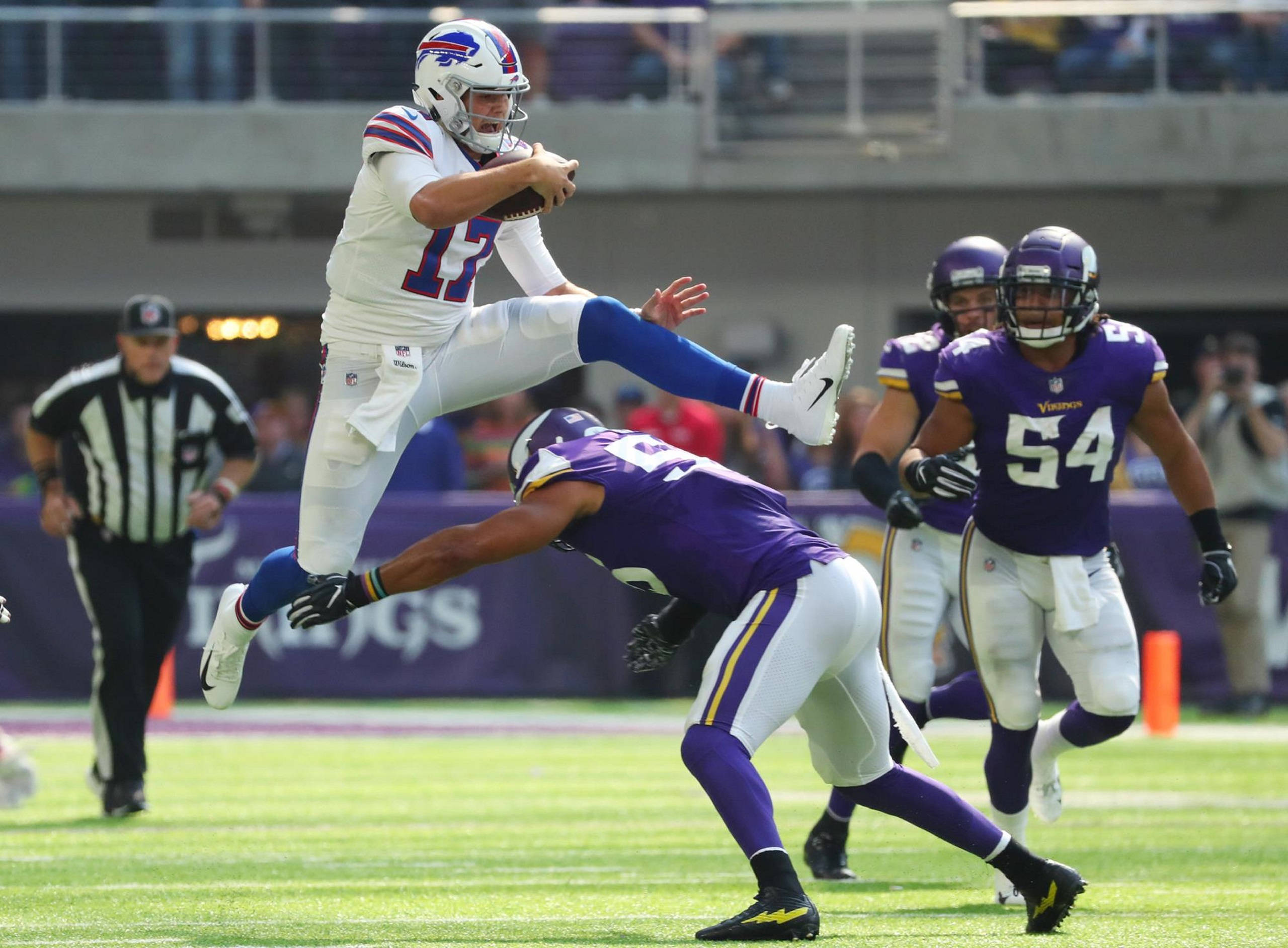 Josh 桌布 壁紙 — 水牛城比爾的四分衛在激烈的NFL比賽中跳過明尼蘇達維京人隊飛撲的防守球員。