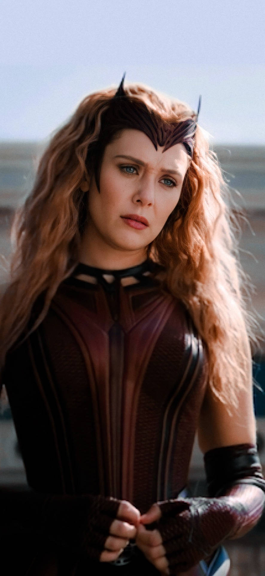 Wanda 桌布 壁紙 — 汪達·馬克希莫夫身穿深棕色服裝，頭戴角狀頭飾，在朦朧的戶外背景下握緊拳頭站立。