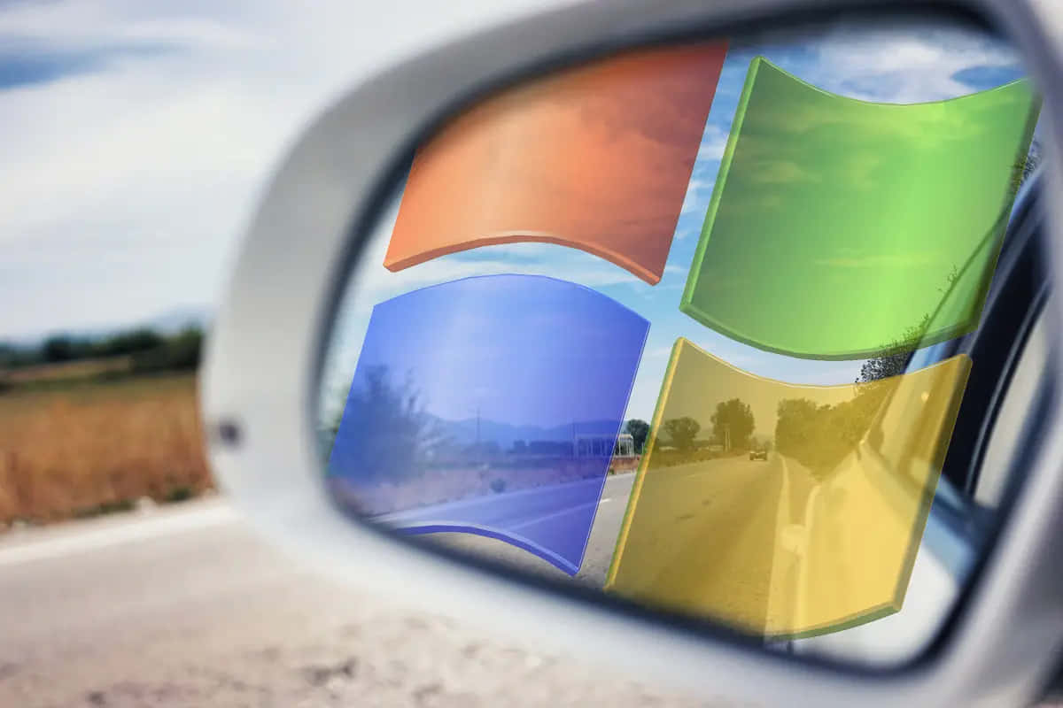 Windows 7 桌布 壁紙 — 汽車側鏡反射出標誌性的Windows標誌，背景是模糊的路邊風景和陰天。