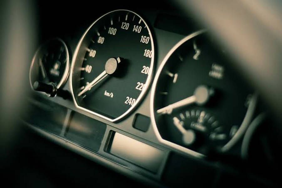 Speed 桌布 壁紙 — 汽車儀表板特寫，速度計和儀表在昏暗光線中柔和發光。