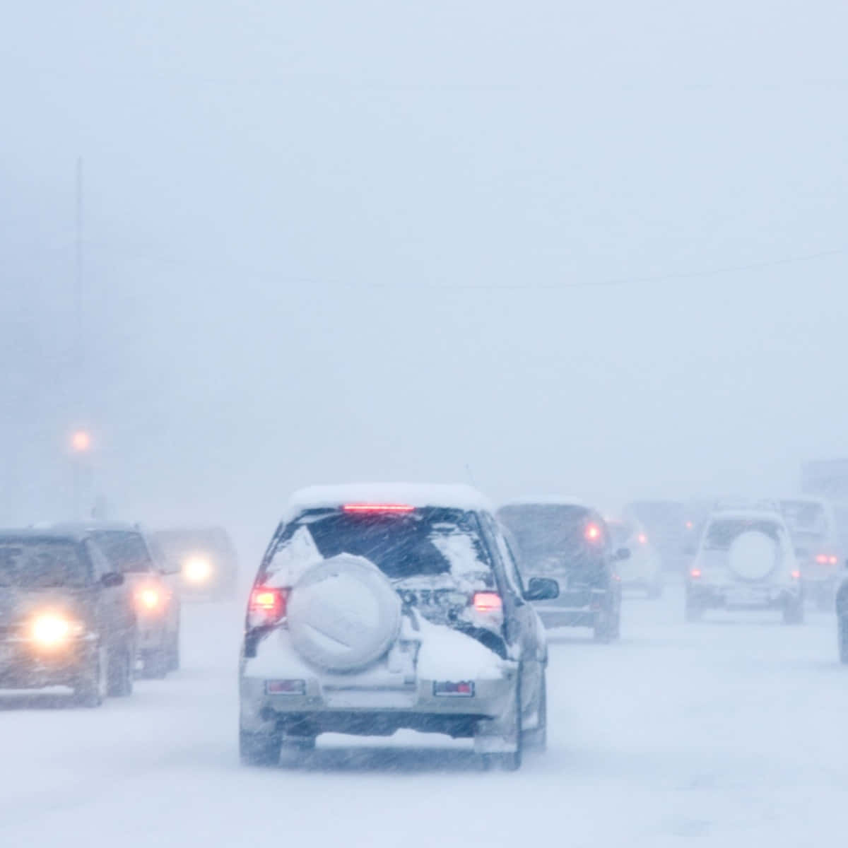 blizzard 桌布 壁紙 — 汽車在暴風雪中行駛，車頭燈穿透結冰道路上的白茫茫暴風雪。