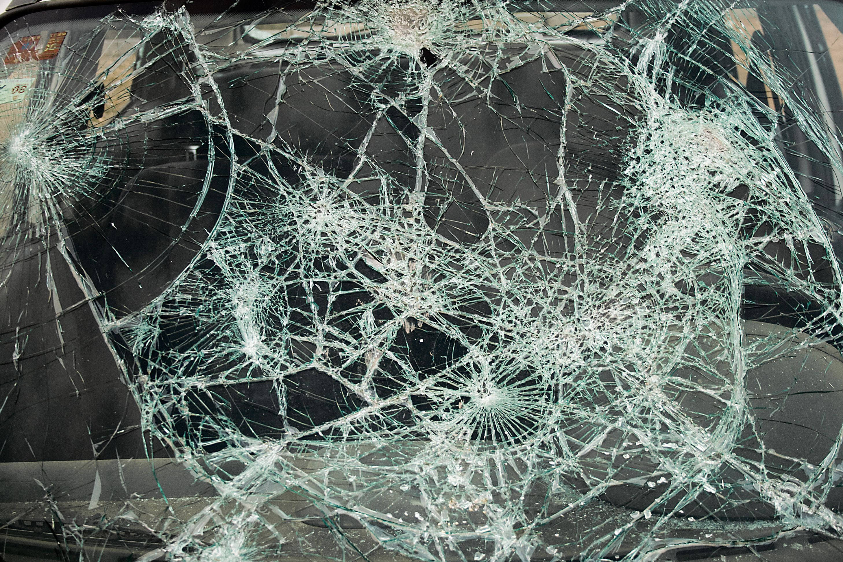 cracked 桌布 壁紙 — 汽車擋風玻璃碎裂的特寫，帶有複雜的蜘蛛網狀裂紋和碎玻璃。