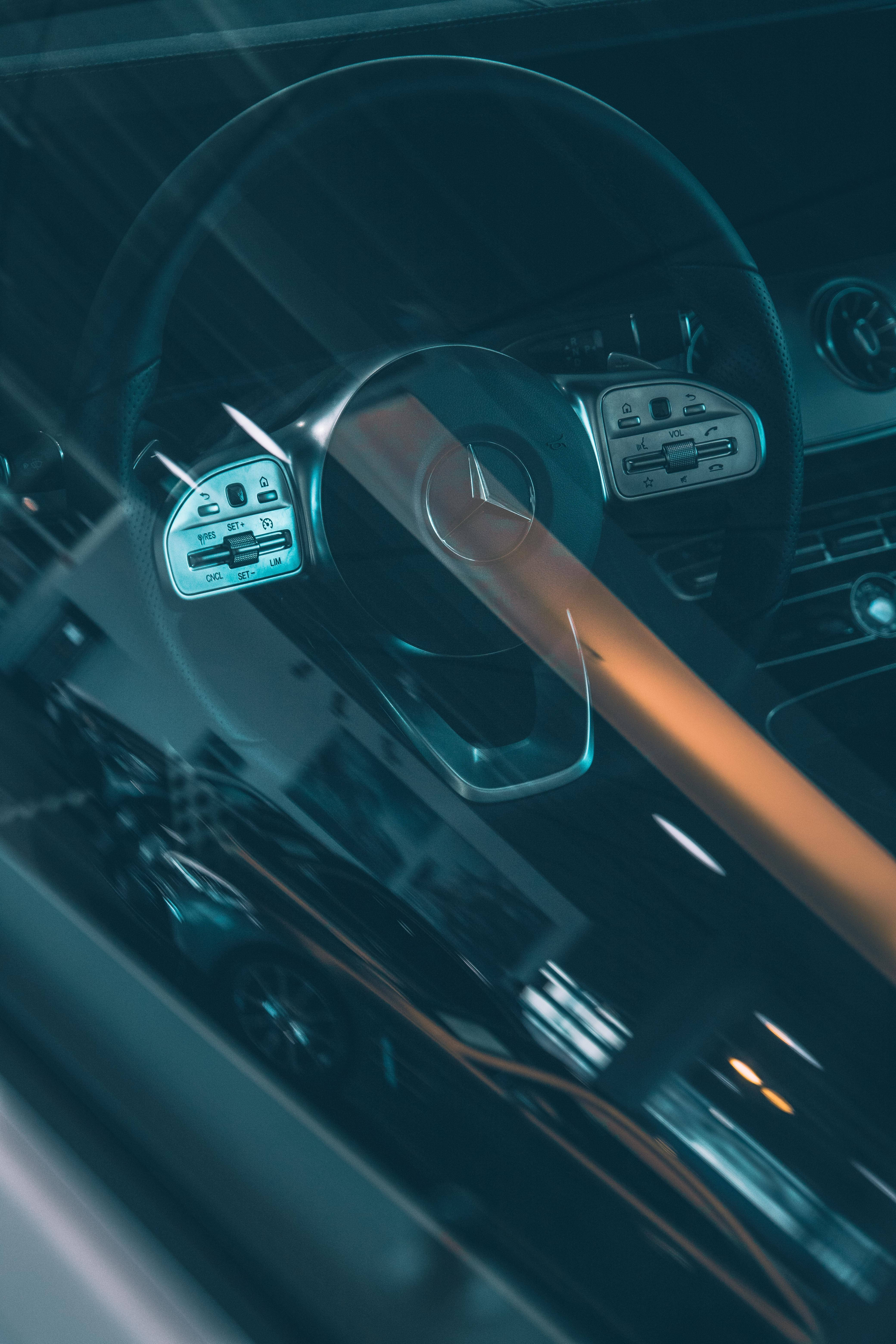 Mercedes 桌布 壁紙 — 汽車方向盤和儀表板的特寫，散發著冷藍光，同時一道溫暖的橙色光束劃過車廂內部。