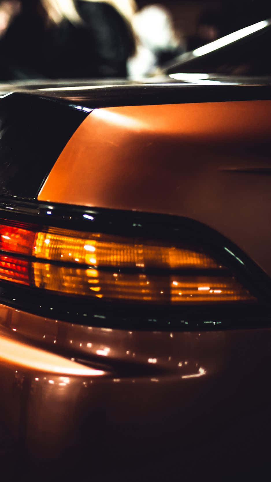 JDM 桌布 壁紙 — 汽車琥珀色尾燈在夜間反射城市燈光的特寫，背景模糊。