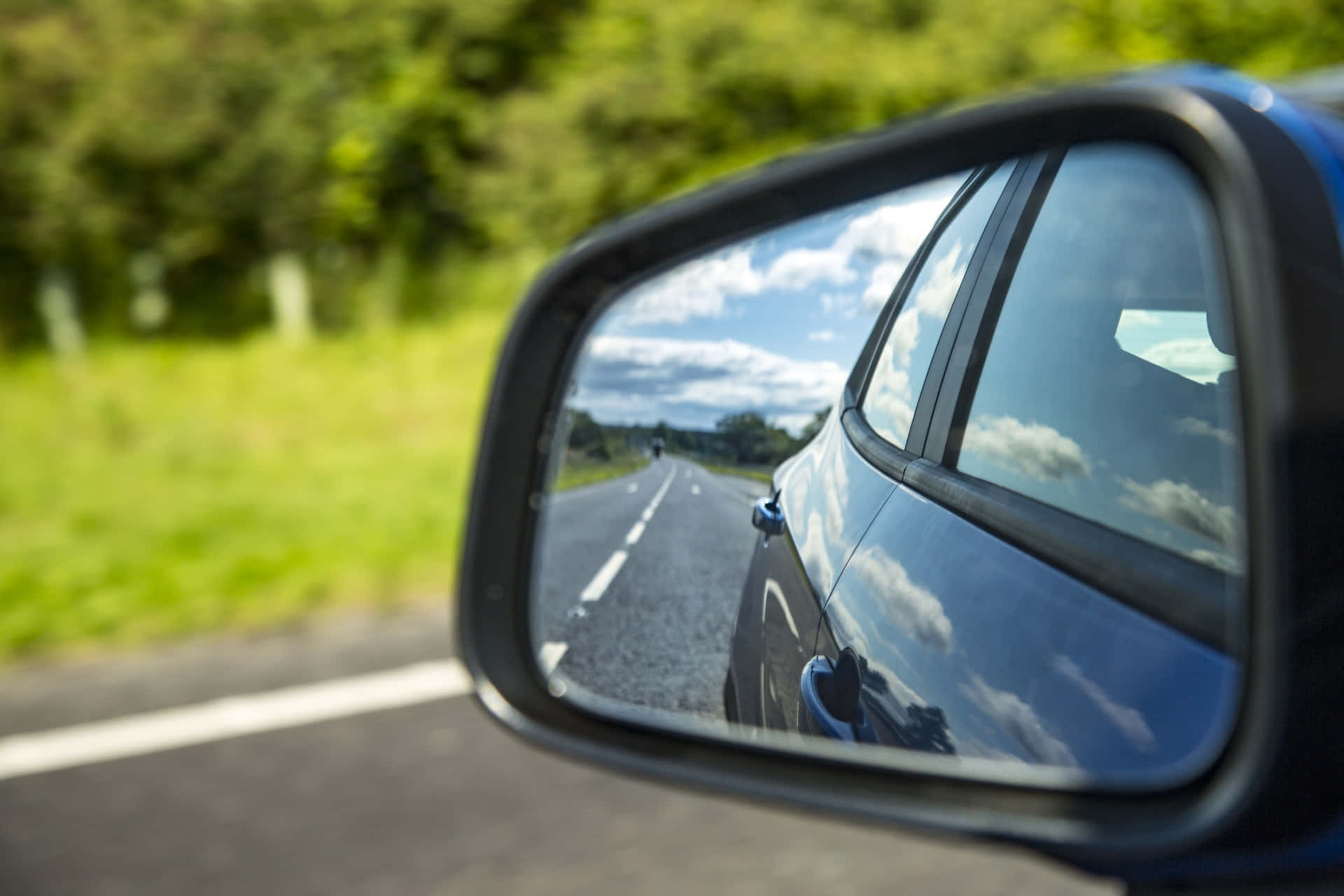 reflection 桌布 壁紙 — 汽車的側鏡反射出一條陽光明媚的道路，在部分多雲的天空下延伸至遠方。