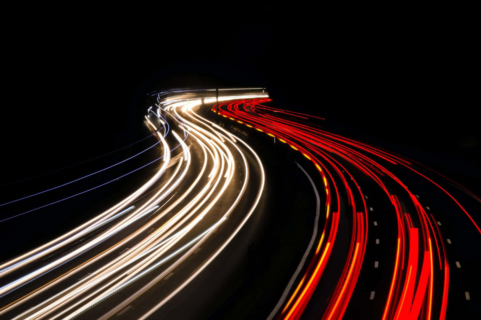 動態桌面 桌布 壁紙 — 汽車的動態光軌在蜿蜒的夜間高速公路上劃過黑暗。