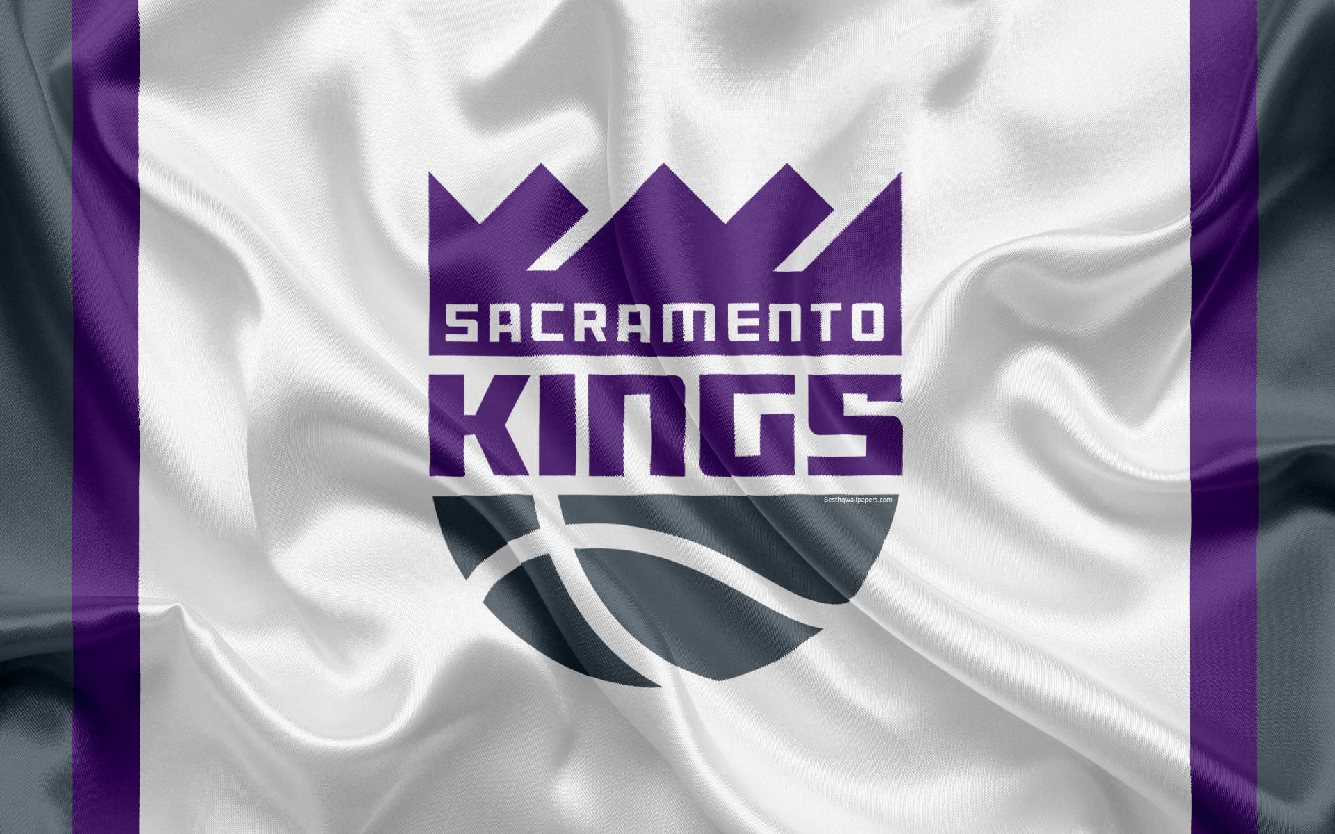 Sacramento 桌布 壁紙 — 沙加緬度國王隊標誌印在飄揚的白色和紫色緞面旗幟上，配有粗體字體和籃球圖案。