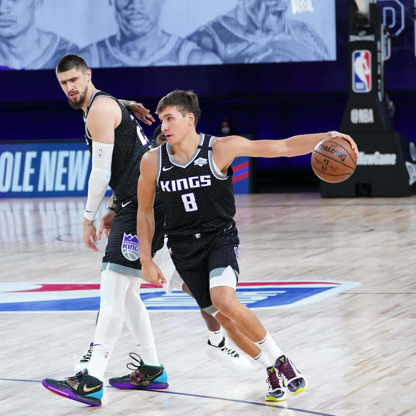 NBA 桌布 壁紙 — 沙加緬度國王隊籃球球員在明亮的場館燈光下，於NBA比賽中運球時被防守。