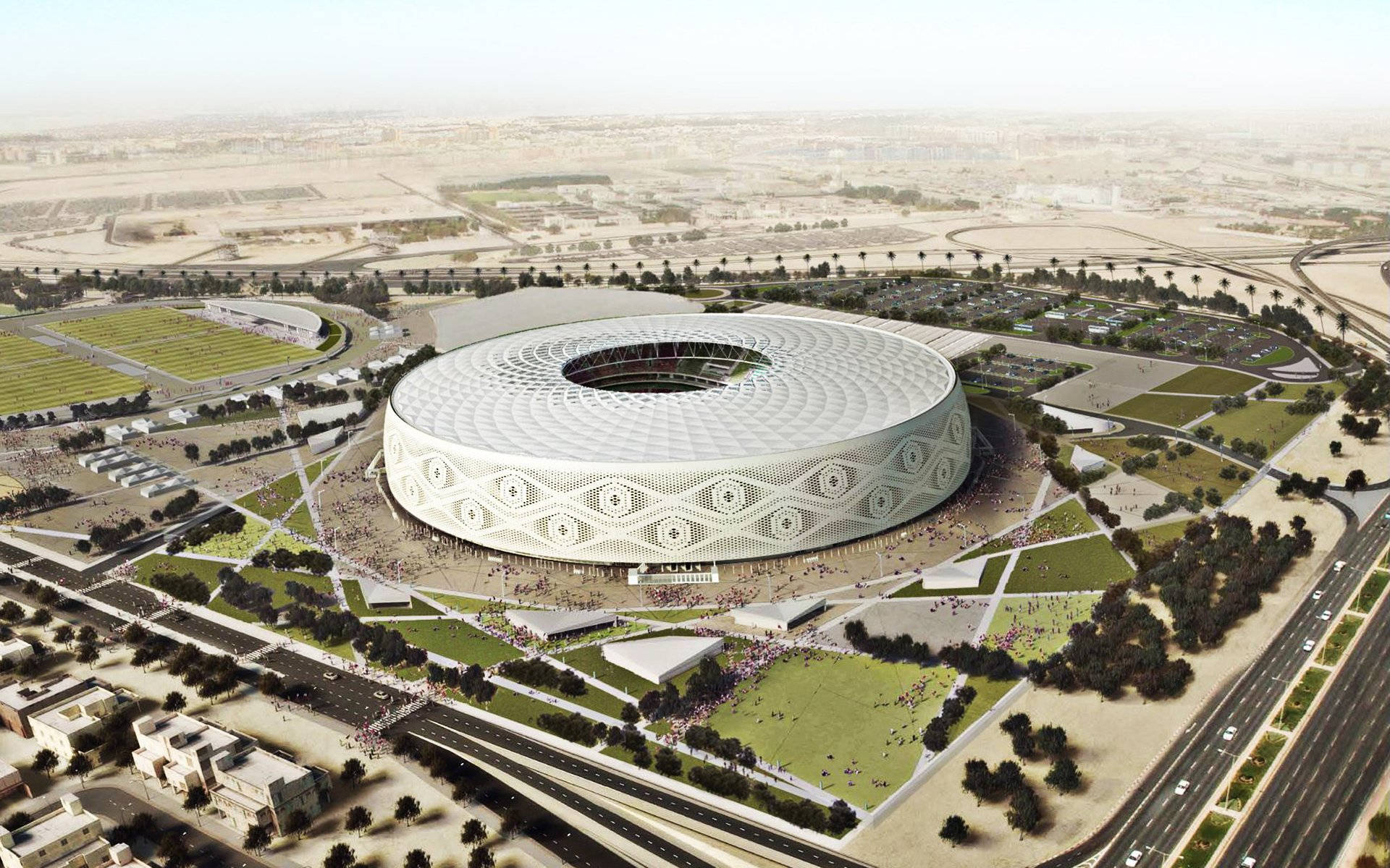 Qatar 桌布 壁紙 — 沙漠景觀中，一個未來主義圓形體育場的鳥瞰圖，帶有幾何圖案，周圍環繞著綠地和道路。