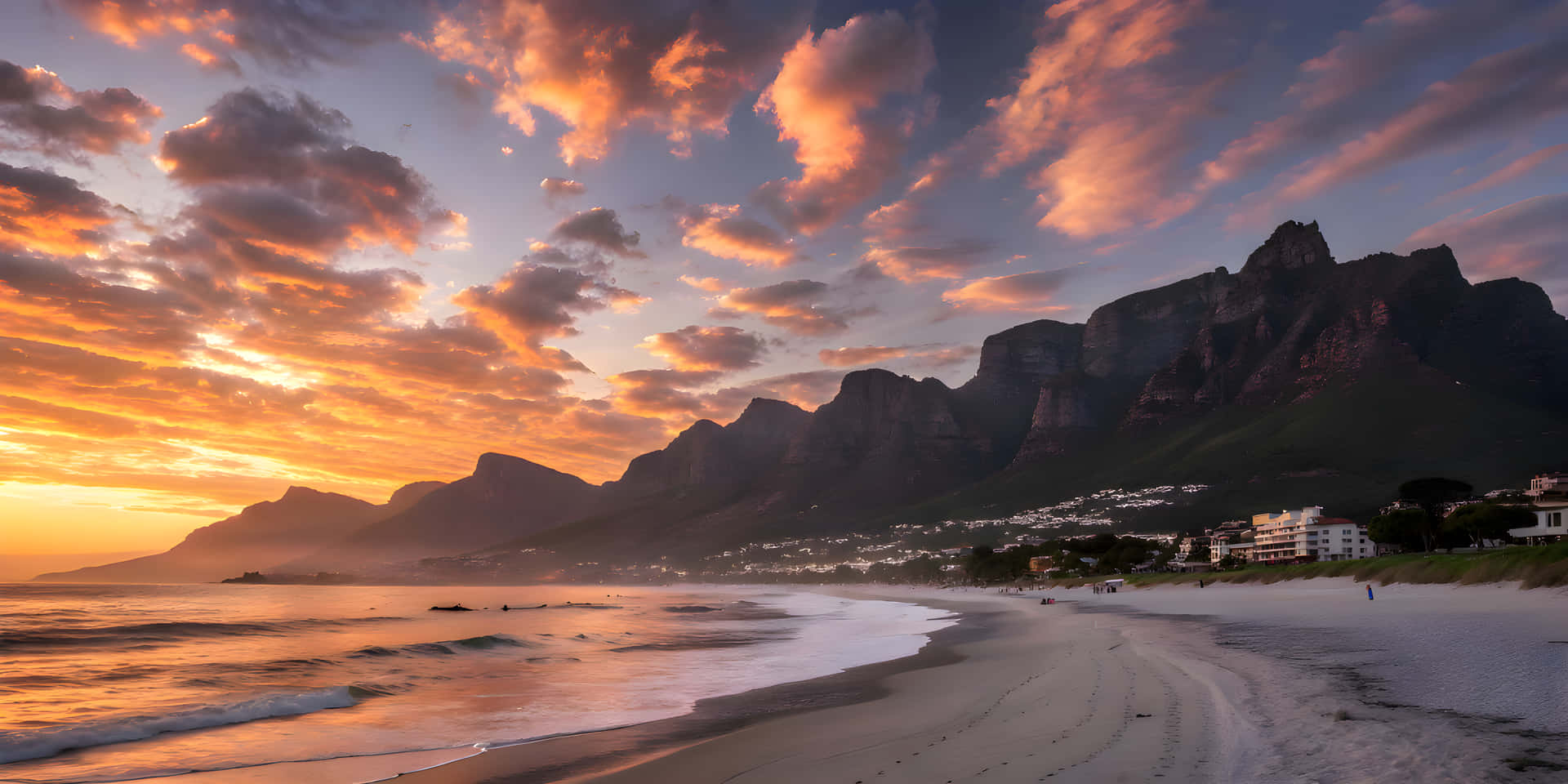 Sunset time in sea beach and little city 壁紙 — 沙灘上壯麗的日落，海浪翻滾，戲劇性的橙色雲彩在崎嶇的山脈和沿海建築上空發光。