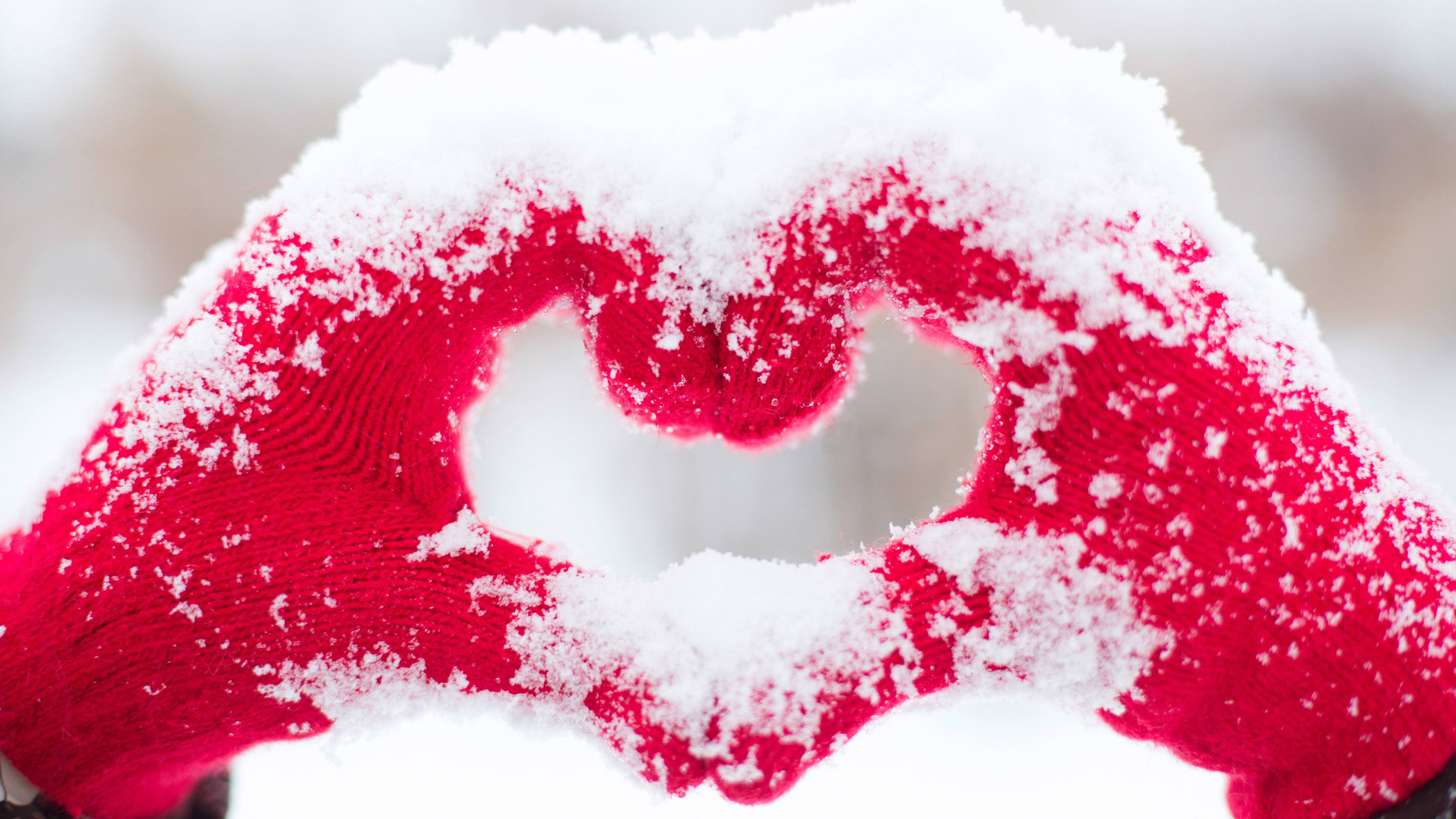 Really Cool Love 桌布 壁紙 — 沾滿雪花的紅色針織手套在柔和冬日背景下形成心形。