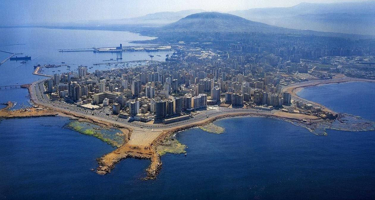 Lebanon 桌布 壁紙 — 沿海城市的鳥瞰圖，坐落於深藍色水域與遠處山脈之間，天空晴朗。