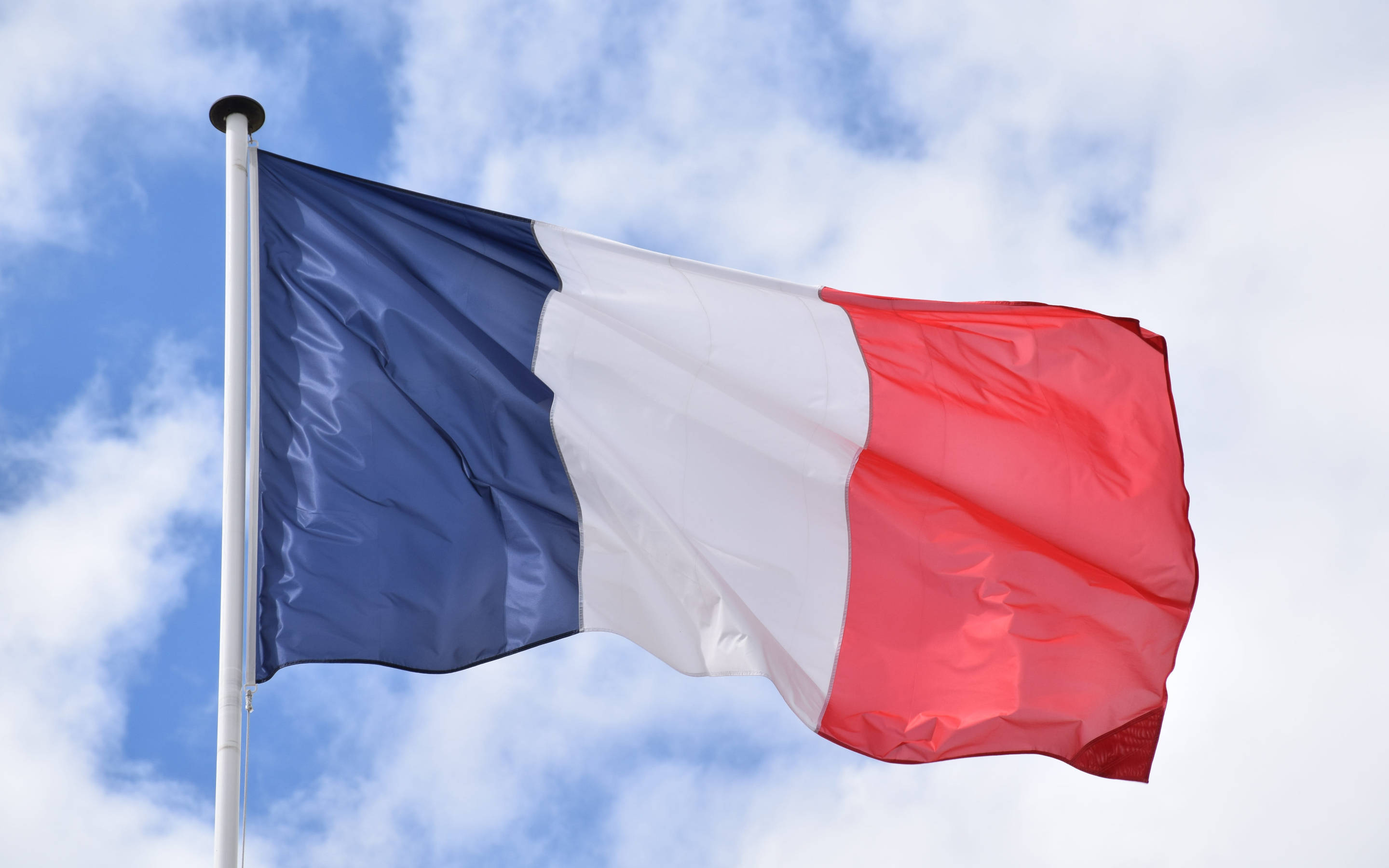 France Flag 桌布 壁紙 — 法國三色旗在藍天白雲下飄揚，動感十足。