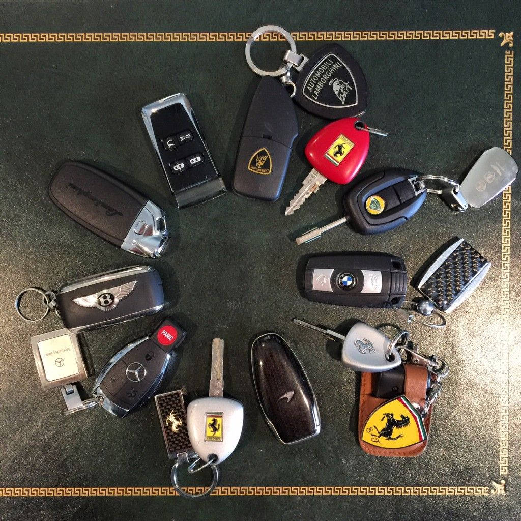 BMW 動圖 桌布 壁紙 — 法拉利、藍寶堅尼、賓利等豪華車鑰匙在帶有金色邊框的深色紋理表面上圓形排列。