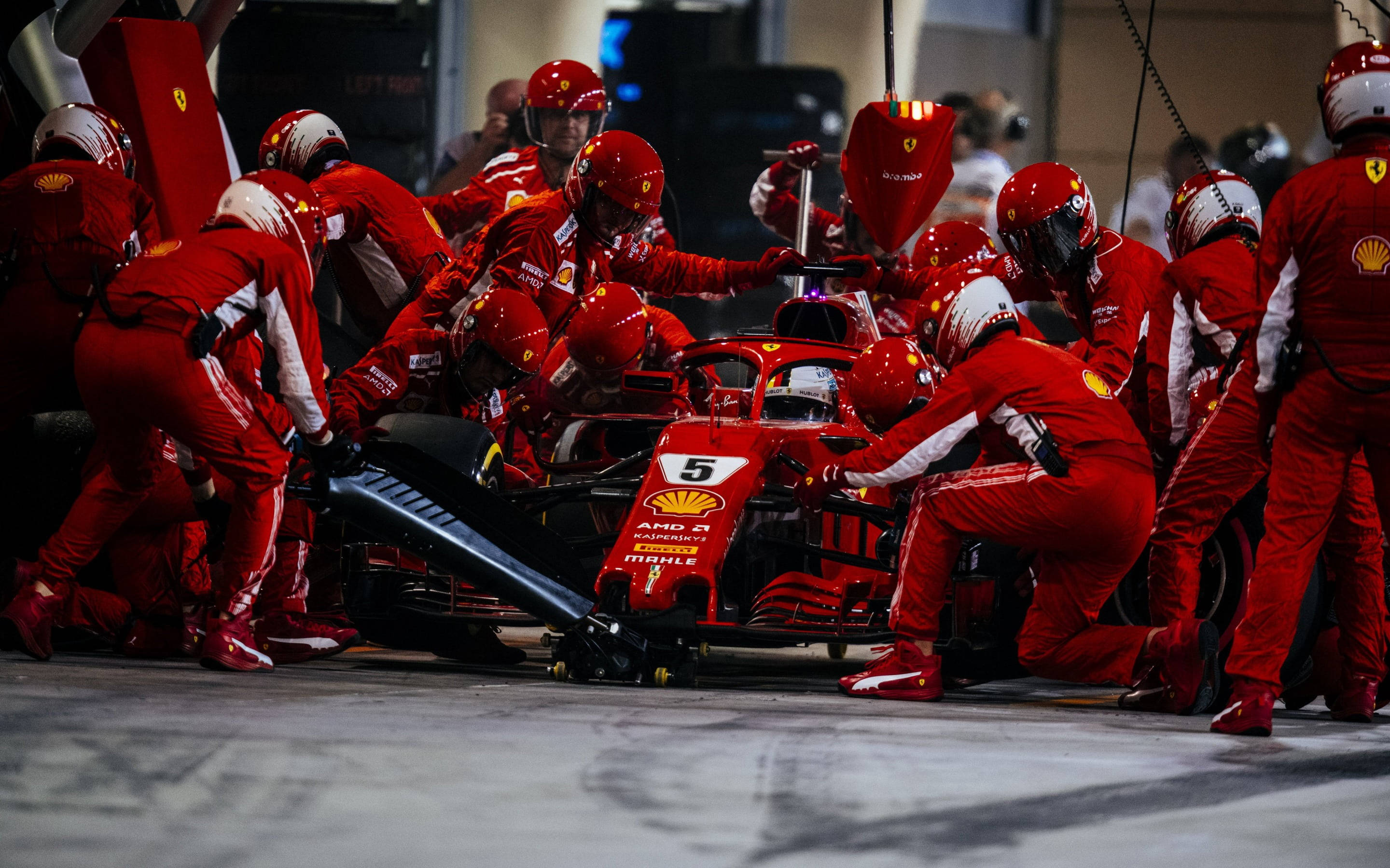 ferrari f1 2018 桌布 壁紙 — 法拉利一級方程式車隊的紅色制服維修人員在明亮的車庫燈光下迅速更換5號車的輪胎。