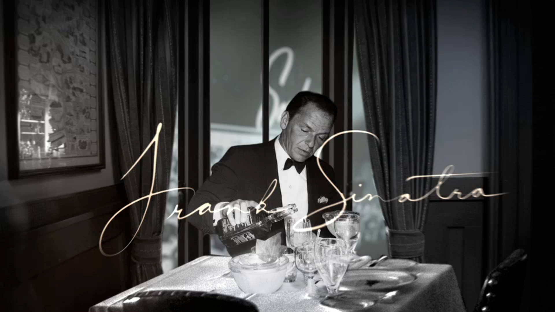 Sinatra 桌布 壁紙 — 法蘭克·辛納屈在燈光昏暗的高級餐廳中倒飲料，餐廳有優雅的窗簾和復古裝飾。