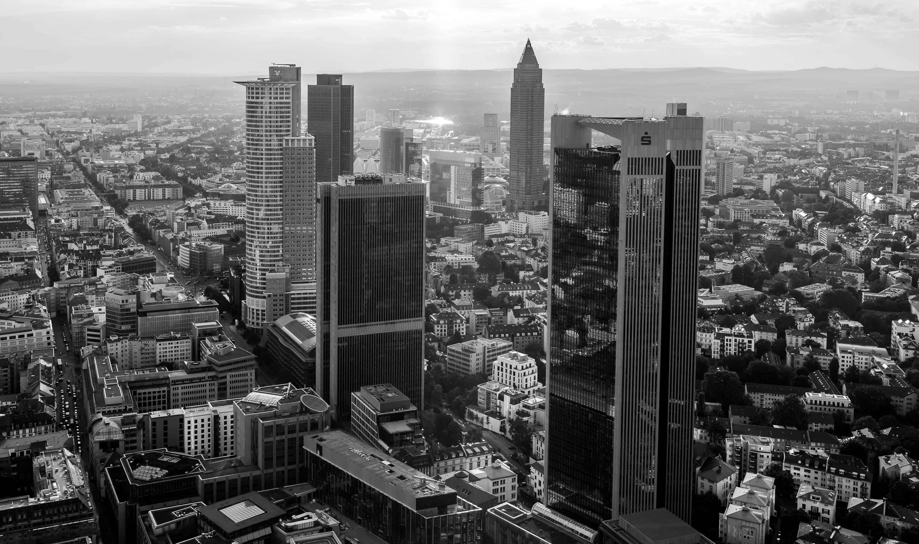 Black And White Cityscape 桌布 壁紙 — 法蘭克福天際線的航拍圖，高聳的摩天大樓刺穿密集城市擴張上方朦朧的天空。