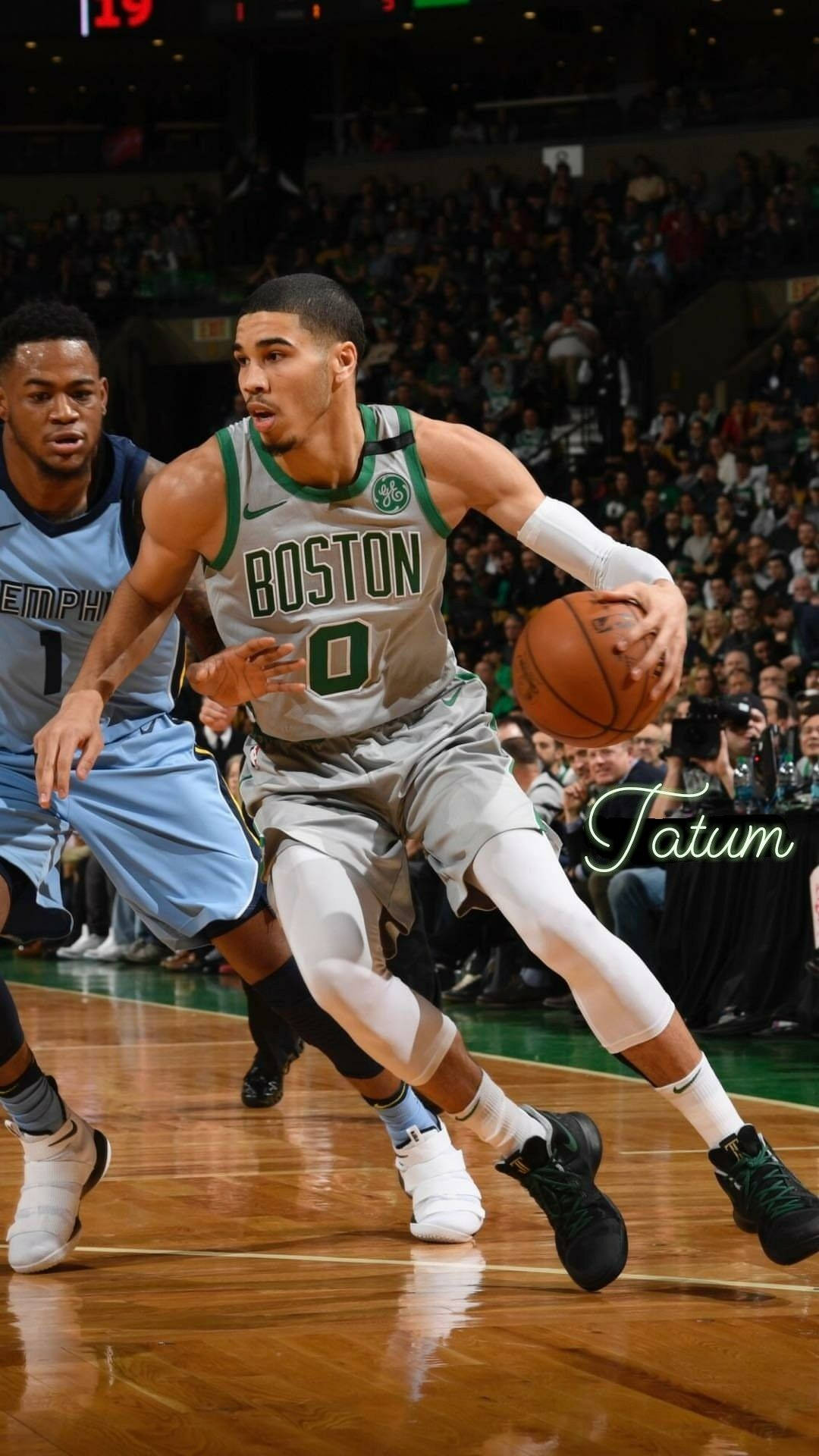 Jayson Tatum 桌布 壁紙 — 波士頓塞爾提克球員傑森·塔圖姆在滿座的球場比賽中，專注地運球，而曼菲斯灰熊的防守球員正在逼近。