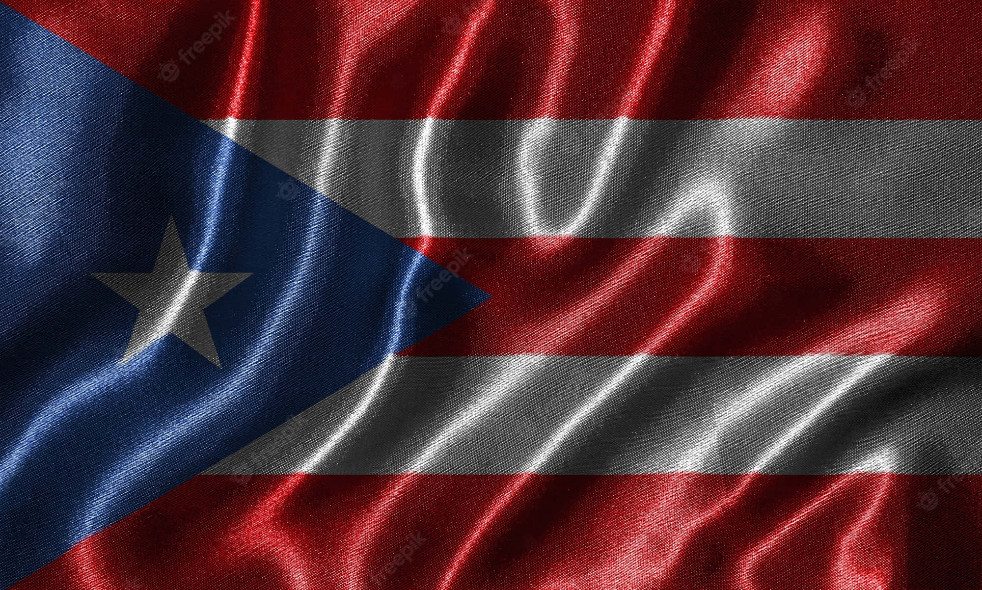 Puerto Rican 桌布 壁紙 — 波多黎各國旗近距離飄揚，呈現豐富的紅、白、藍色，藍色三角形上有一顆白色星星。