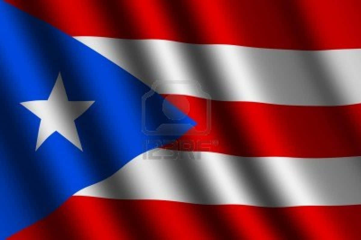 Puerto Rican 桌布 壁紙 — 波多黎各旗幟動態飄揚，帶有鮮明的紅、白、藍條紋，以及藍色三角形上的白色星星。