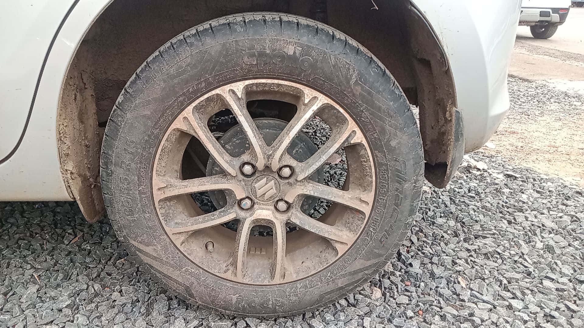 Dirty 桌布 壁紙 — 泥濘汽車輪胎在礫石上的特寫，可見輪胎花紋及合金輪圈細節。
