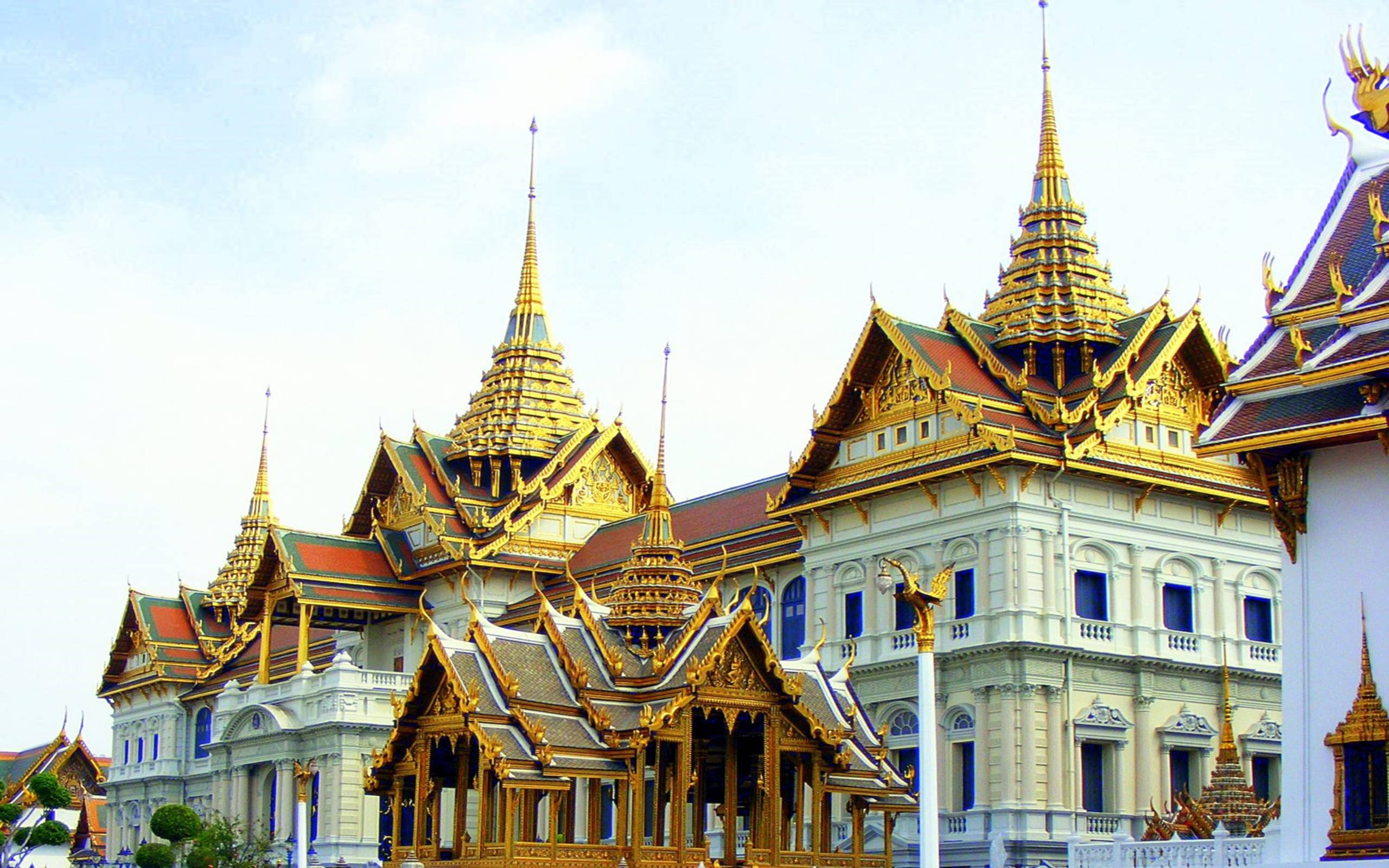 Bangkok 桌布 壁紙 — 泰國皇宮宏偉的金色尖頂和華麗屋頂在明亮的天空下閃閃發光。