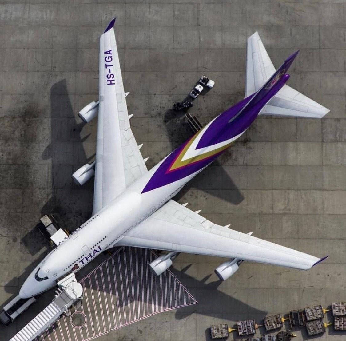 Airport 桌布 壁紙 — 泰國航空空中巴士A380停泊在機場閘口的俯瞰航拍圖，附近有地勤人員和行李車。