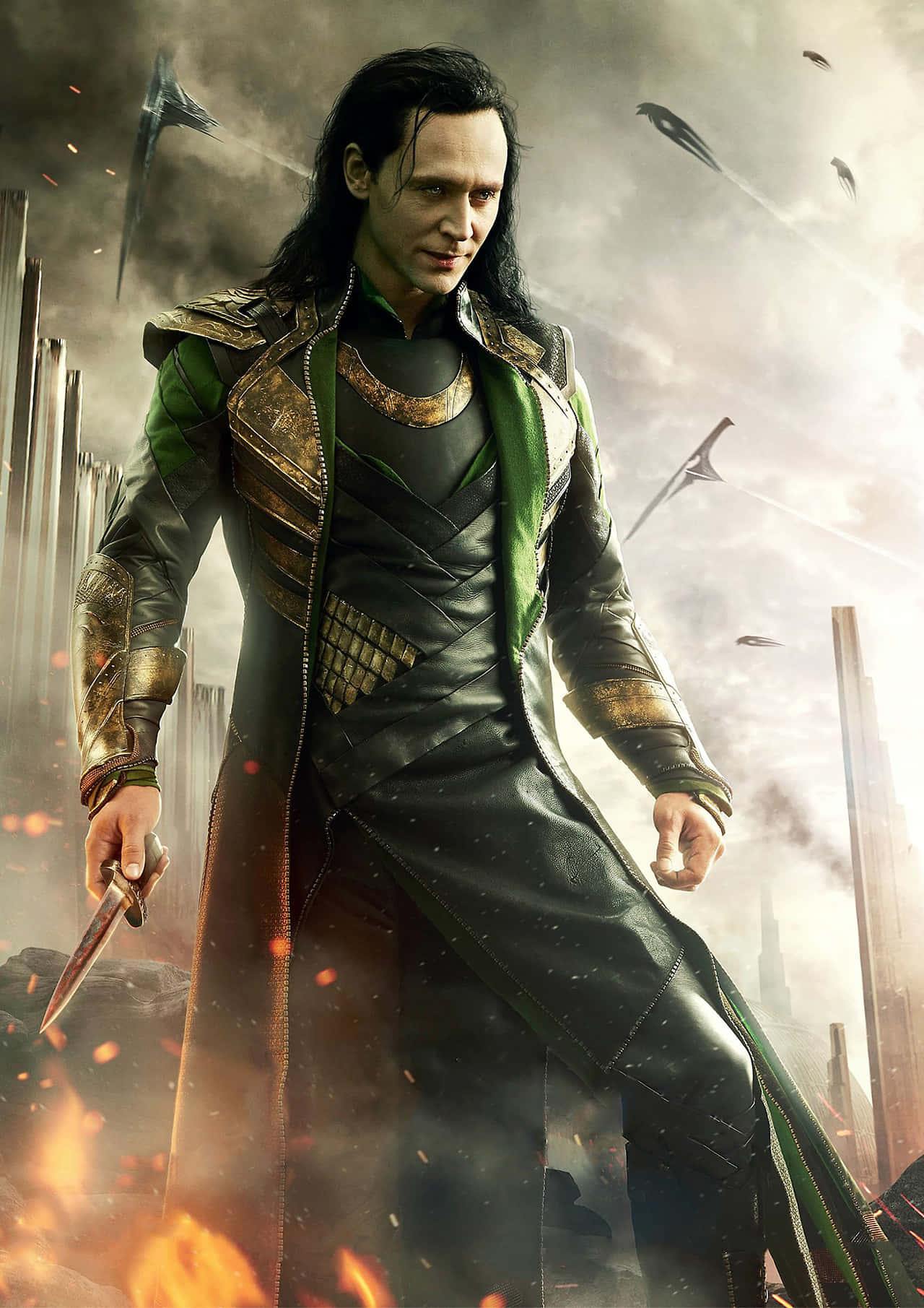 Marvel Loki 桌布 壁紙 — 洛基在滿佈戰鬥痕跡的城市景觀中挑釁地站立，手持匕首，周圍燃燒的碎片和飛舞的刀片旋轉。