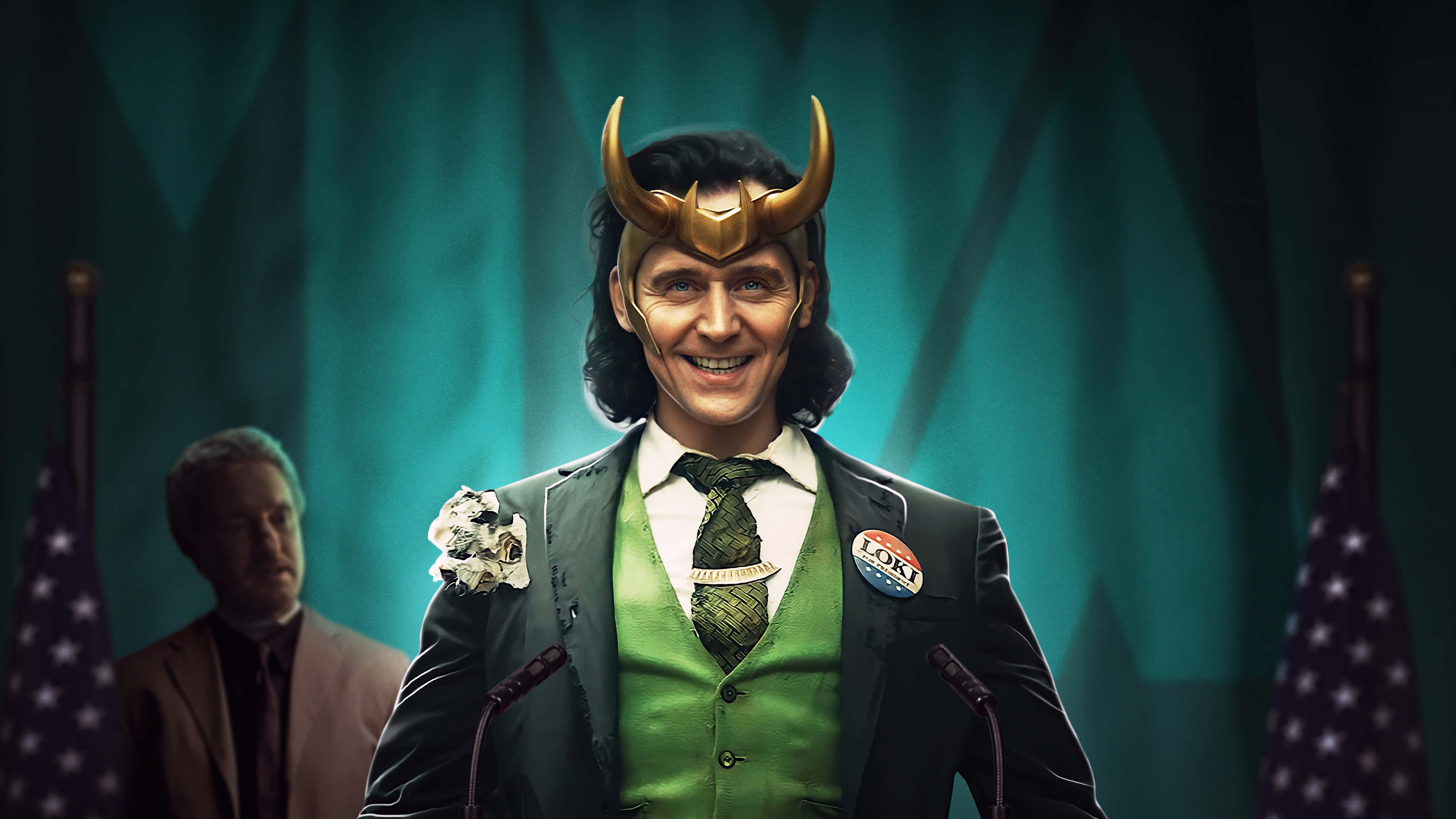 Marvel Loki 桌布 壁紙 — 洛基身穿綠色背心、戴著角盔，在兩旁有美國國旗的講台上微笑。