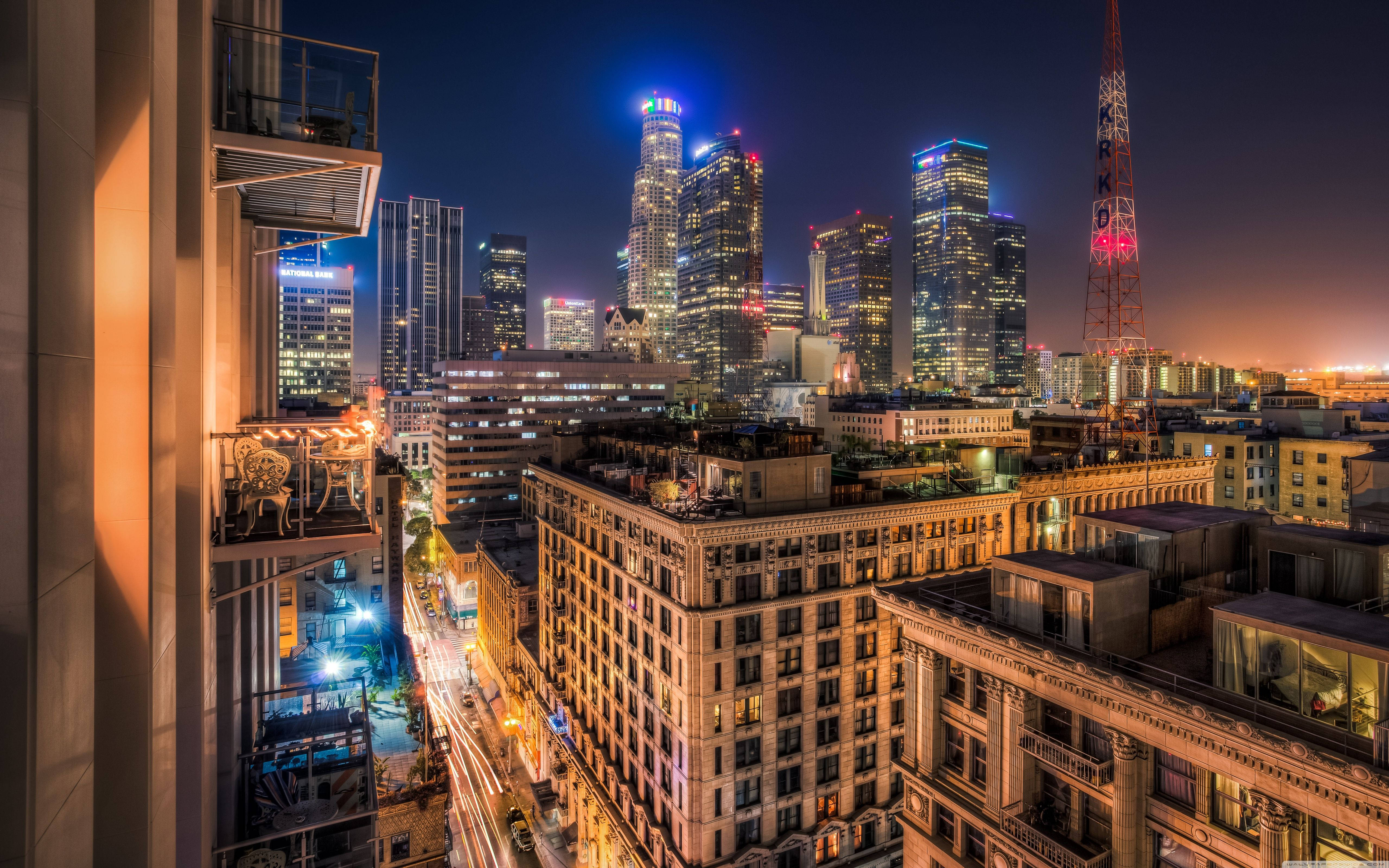 洛杉磯 4K 桌布 壁紙 — 洛杉磯充滿活力的夜景，發光的摩天大樓和溫暖的路燈照亮了繁華的城市峽谷。