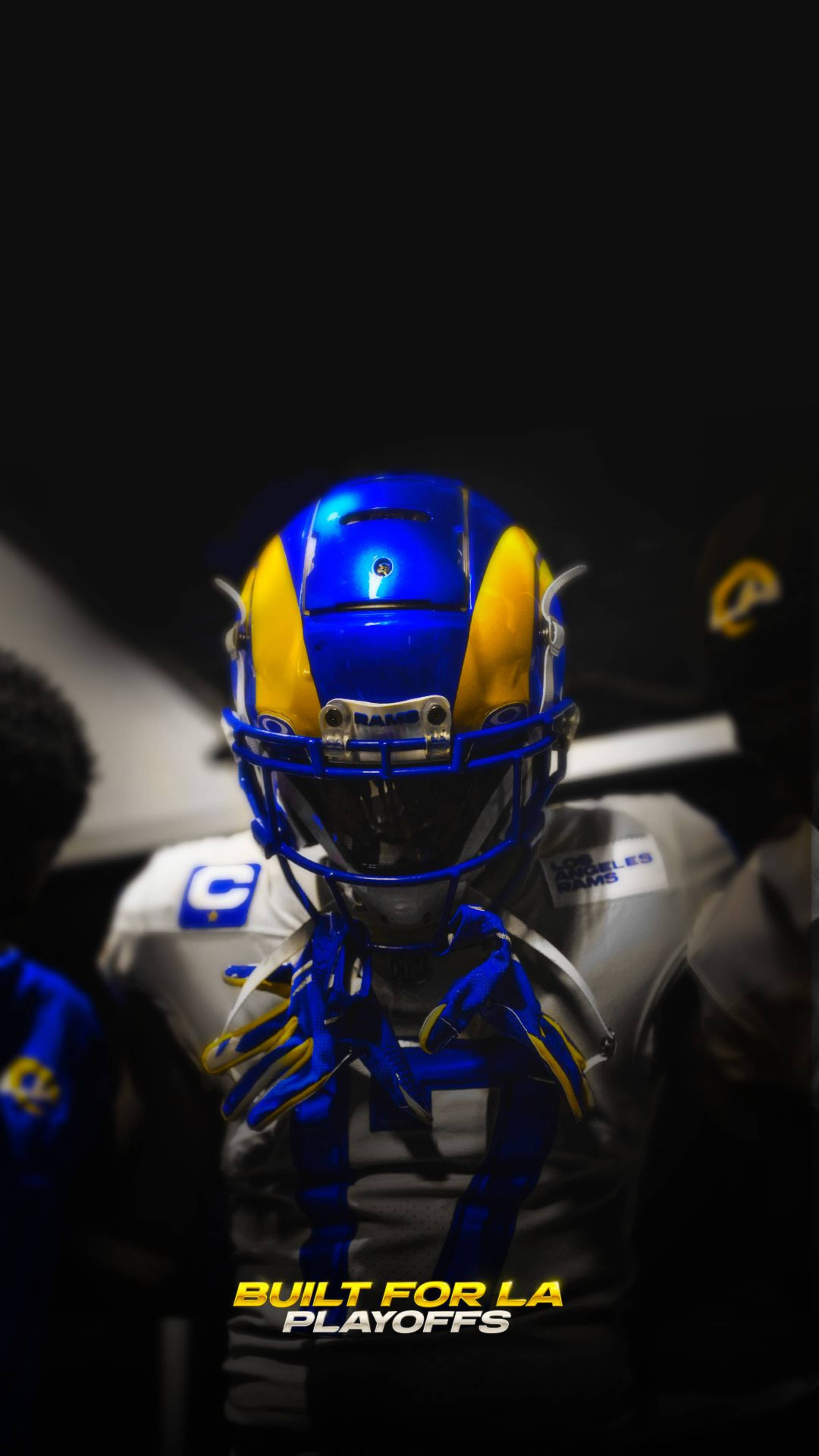 Rams 桌布 壁紙 — 洛杉磯公羊隊美式足球員的特寫，戴著藍金色頭盔，在黑暗背景下有強烈燈光。
