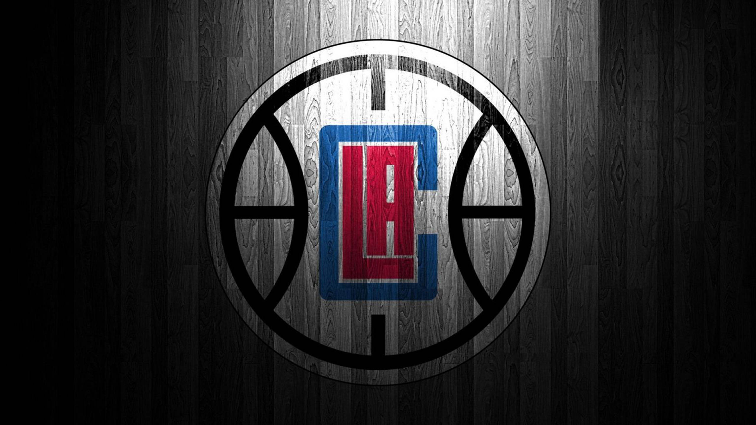 Clippers 桌布 壁紙 — 洛杉磯快艇隊標誌居中放置在深色木質籃球場紋理上，帶有戲劇性燈光。