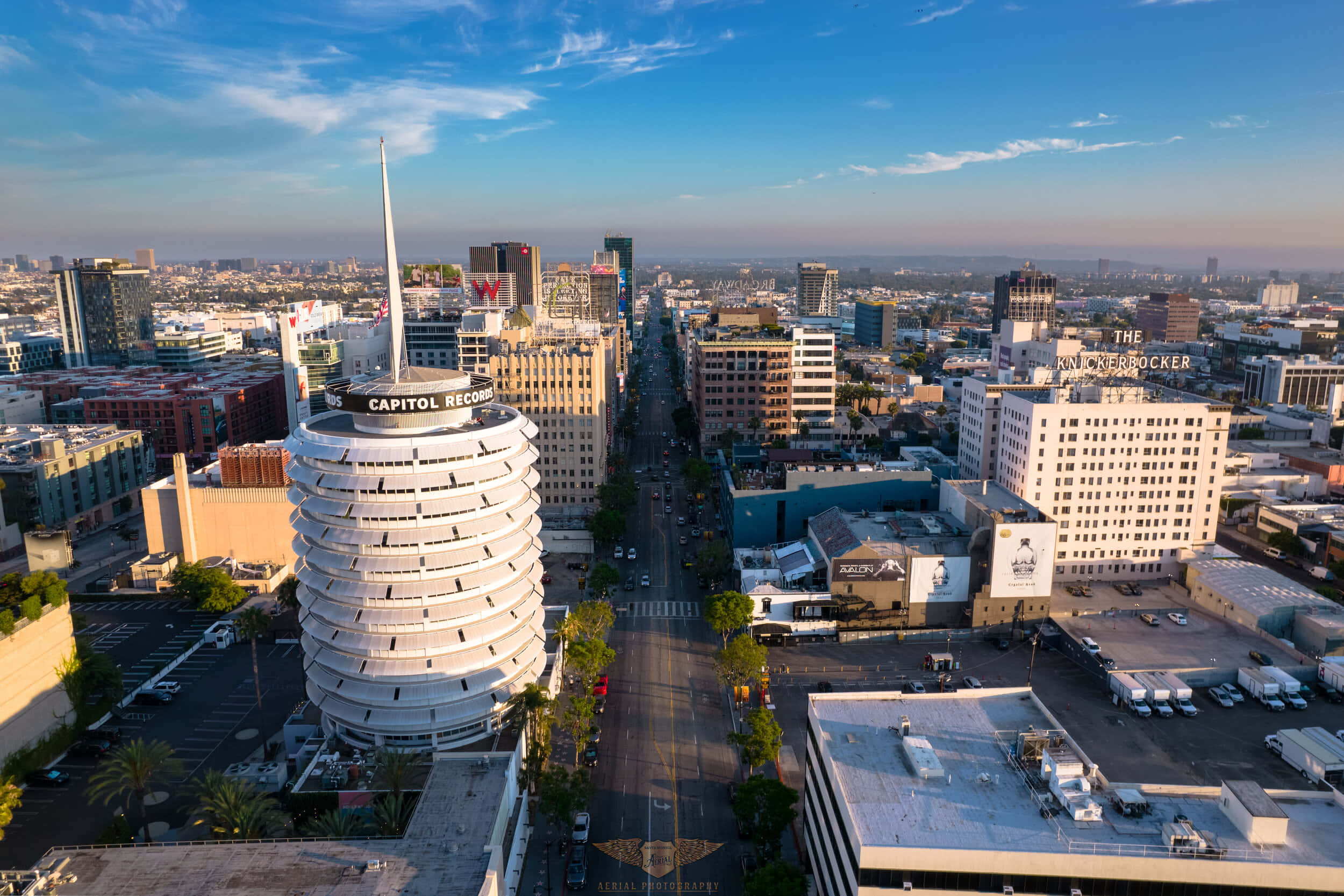 Road 桌布 壁紙 — 洛杉磯標誌性 Capitol Records 大樓的鳥瞰圖，陽光普照的街道和城市天際線在藍天下展現。