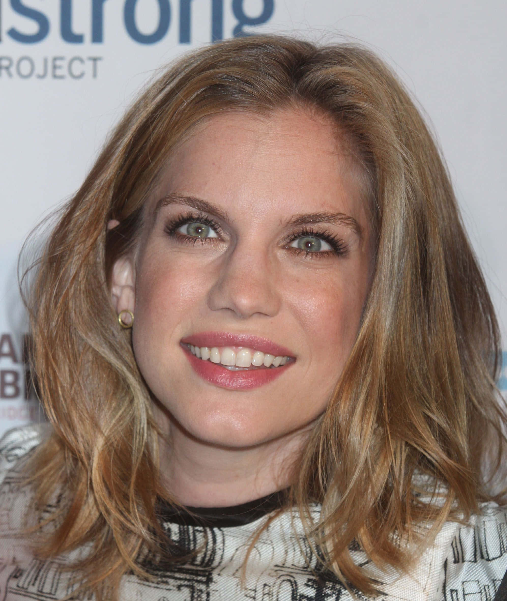 anna chlumsky 桌布 壁紙 — 活動中一位微笑女性的特寫肖像，她有波浪金髮和綠色眼睛。