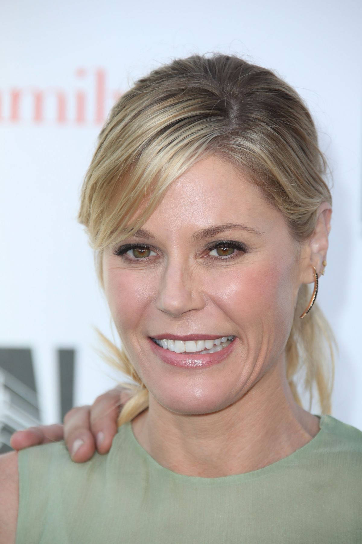 Celebrity 桌布 壁紙 — 活動中一位微笑金髮女子身穿綠色上衣、手搭在肩上的特寫肖像。