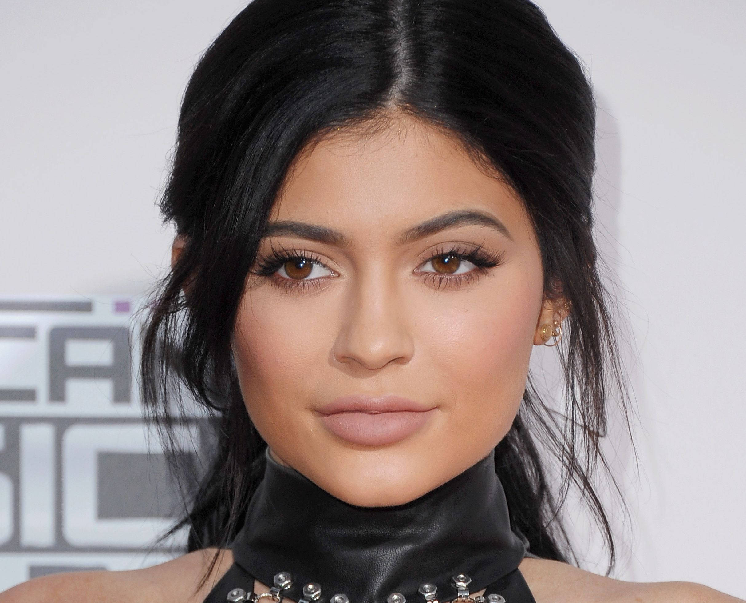 Kylie 桌布 壁紙 — 活動中一位深色頭髮、大膽化妝的女性佩戴黑色皮革頸鍊的特寫肖像。
