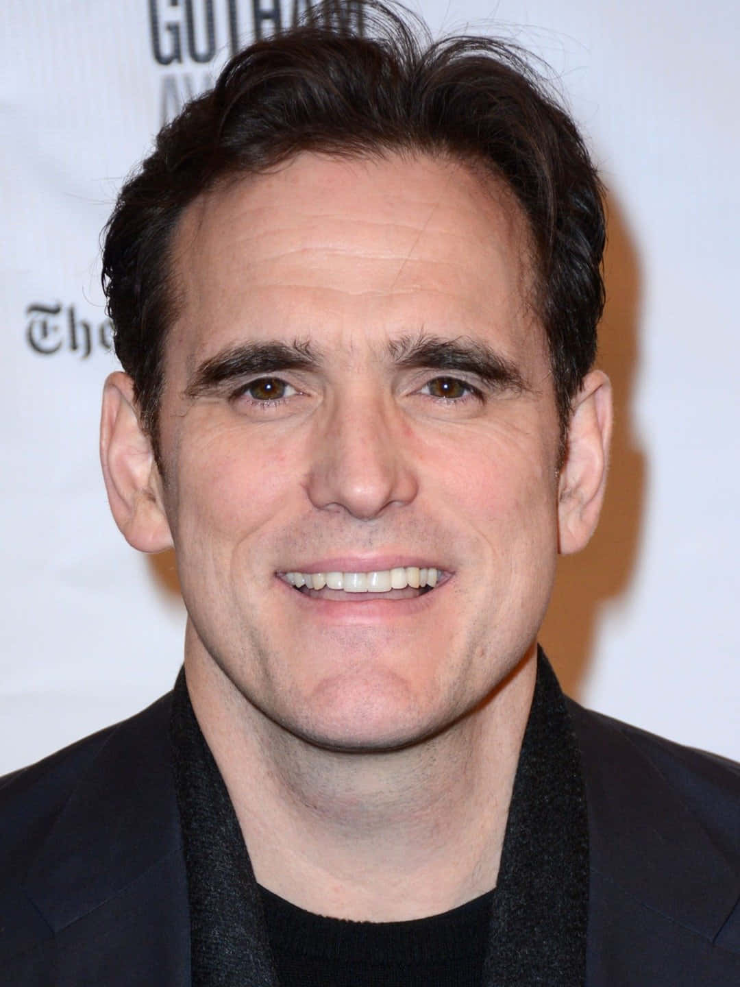 matt dillon 桌布 壁紙 — 活動中一位黑髮微笑男士穿著黑色西裝和圍巾的特寫肖像。