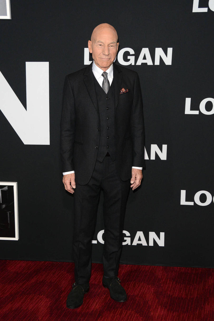 Celebrity 桌布 壁紙 — 派翠克·史都華身穿俐落黑色細條紋西裝，在印有「LOGAN」標誌的背景前，站在紅地毯上。