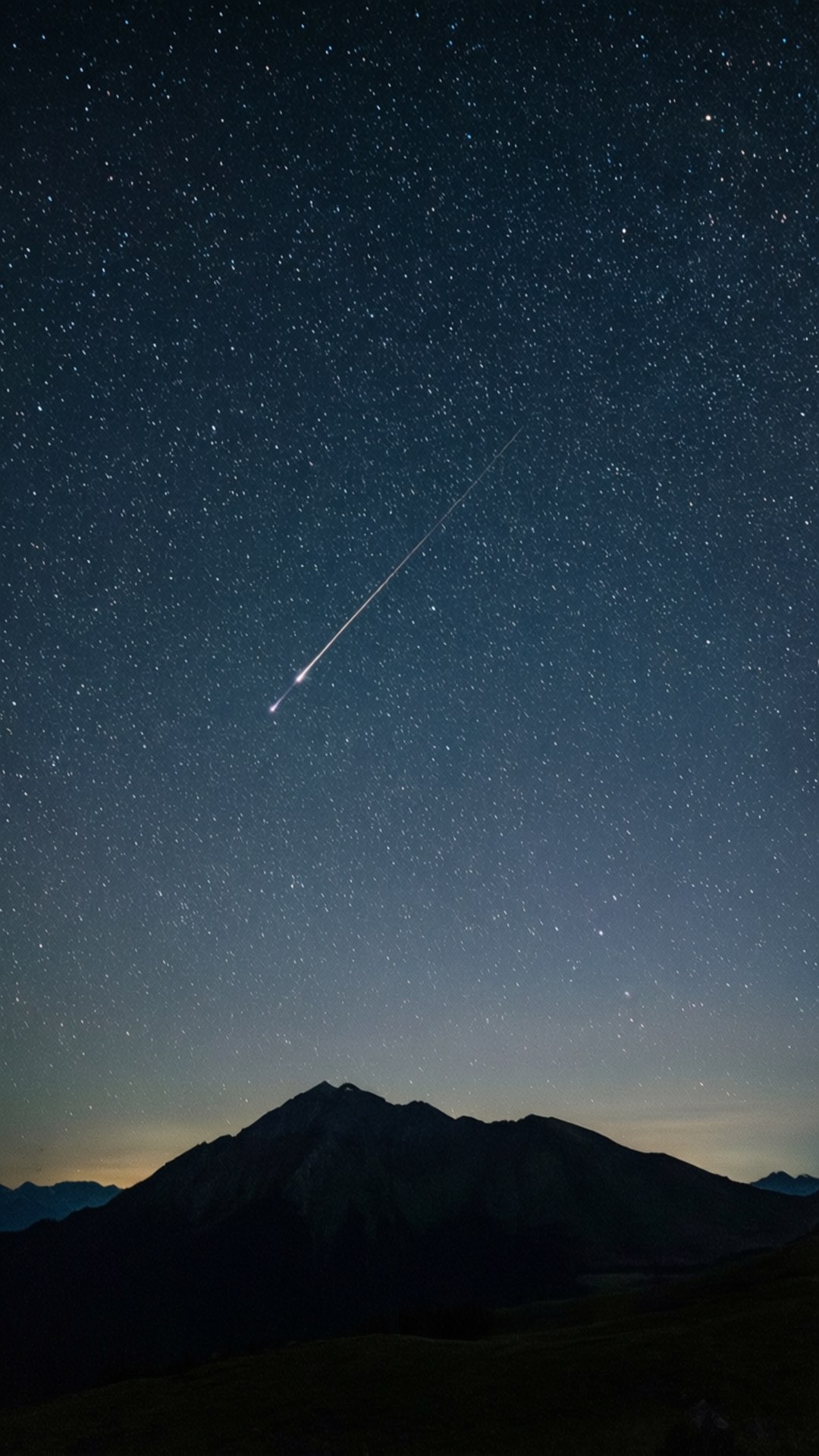 流星之夜 壁紙 — 一顆明亮的流星劃過黑暗山巒剪影之上的星空夜空。