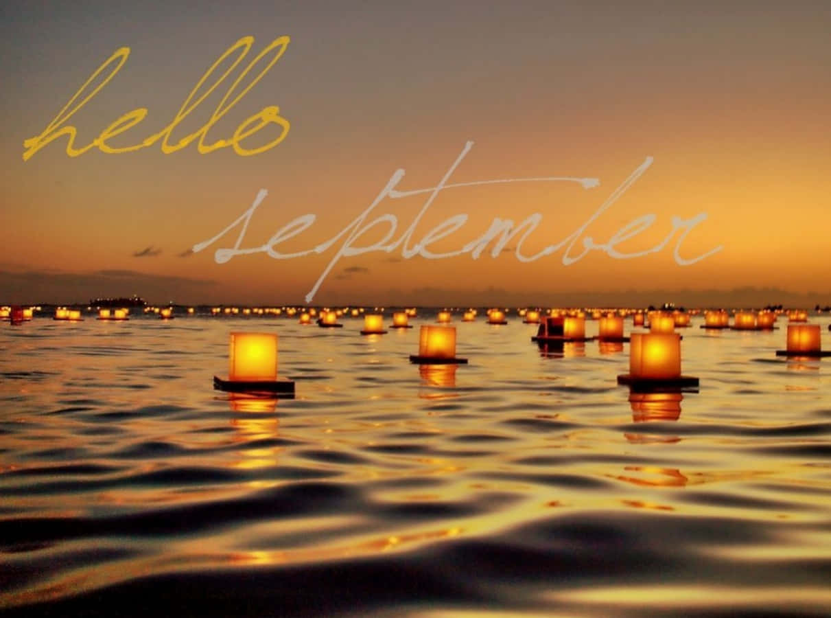 Hello 桌布 壁紙 — 浮動燈籠在金色夕陽天空下的漣漪水面上溫暖發光，並有斜體文字寫著 hello september。