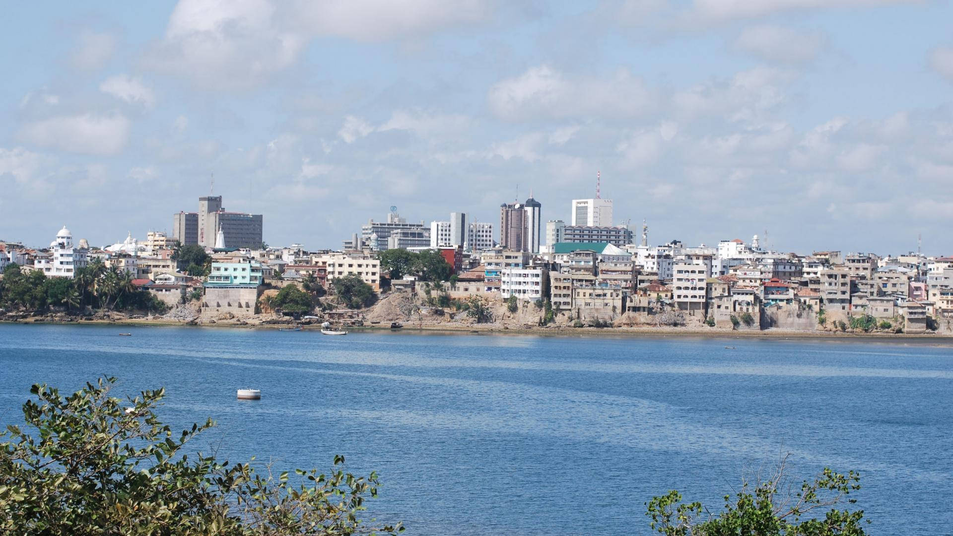 Liberia 桌布 壁紙 — 海岸城市景觀，現代與傳統建築沿著平靜的藍色海灣，天空部分多雲。