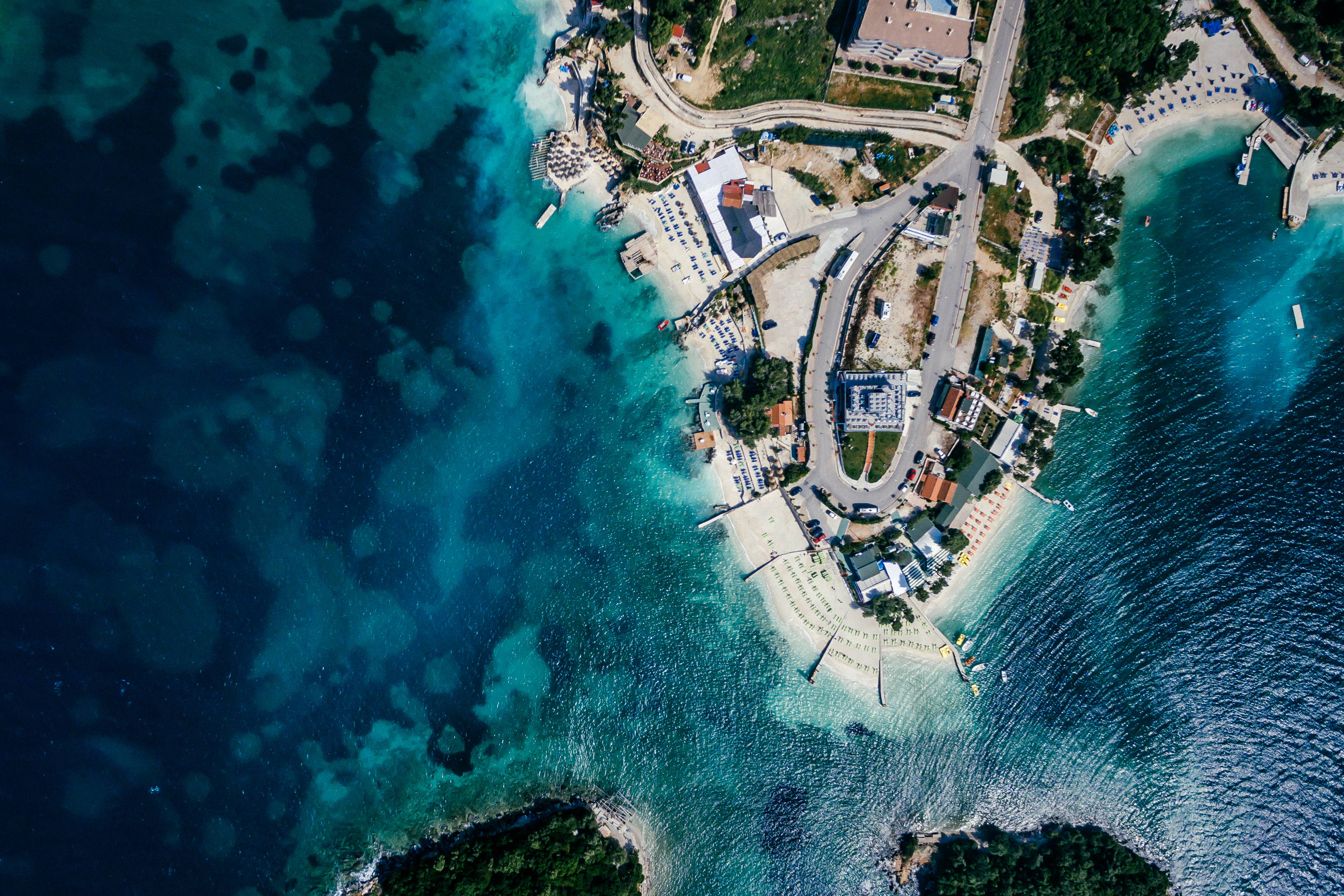 Albania 桌布 壁紙 — 海岸度假村的鳥瞰圖，擁有碧綠的海水和白色沙灘，四周環繞著綠植。