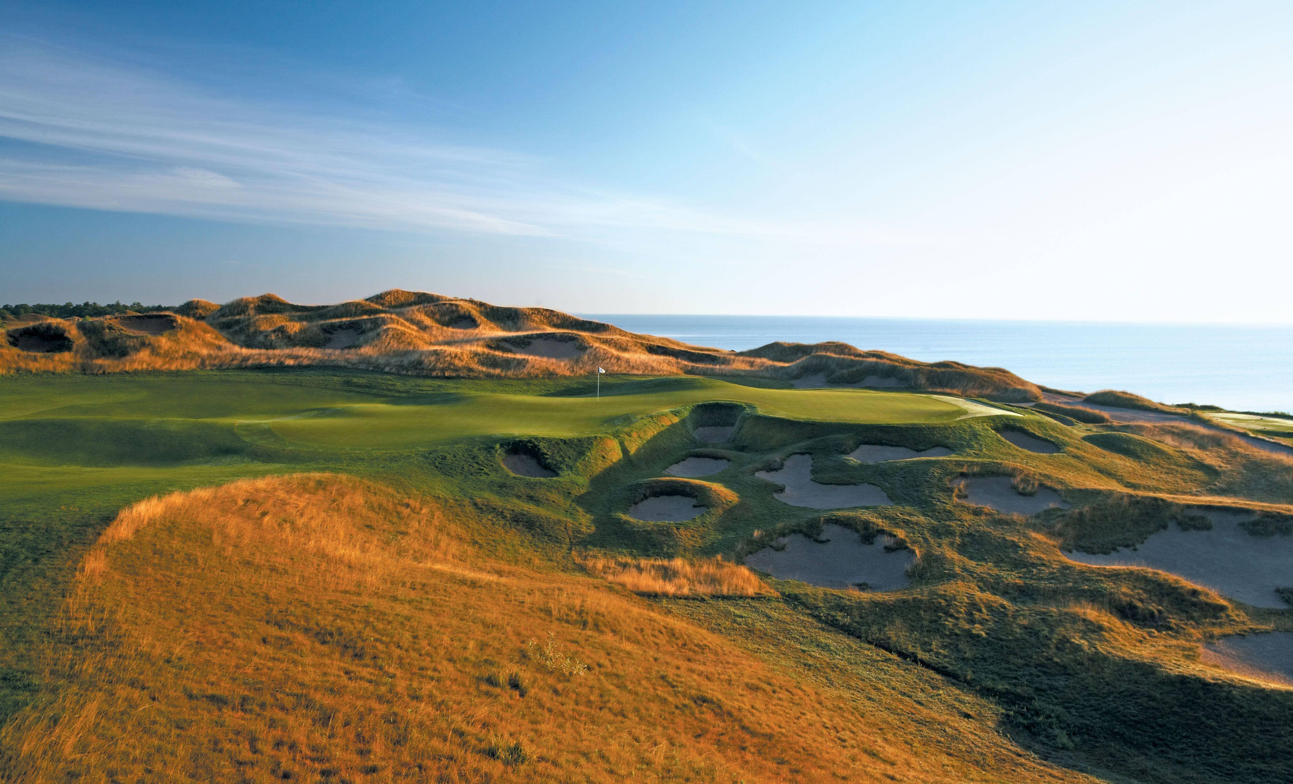 Pga 桌布 壁紙 — 海岸高爾夫球場的鳥瞰圖，擁有起伏的綠色球道、沙丘和沐浴在金色日出光線中的海洋地平線。