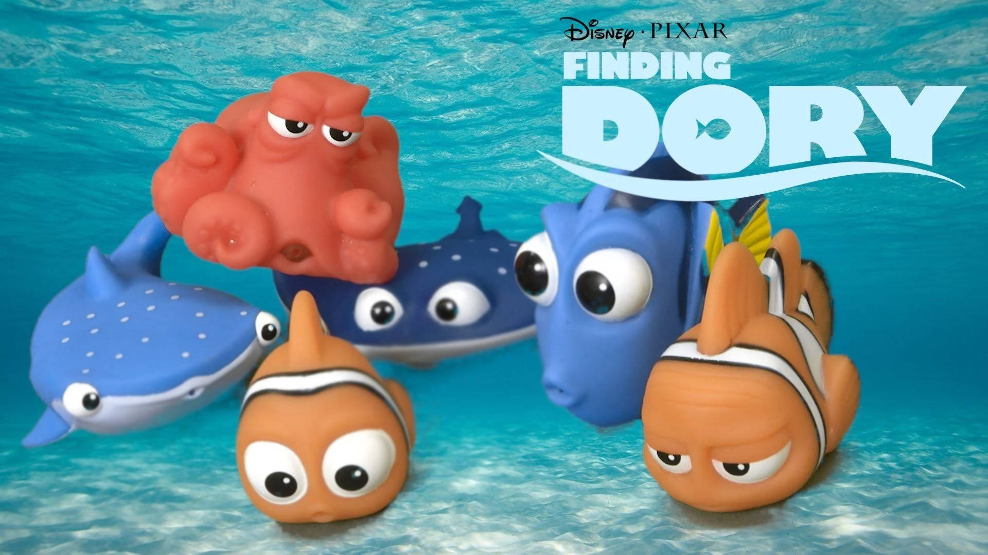 Dory 桌布 壁紙 — 海底場景，Finding Dory 角色以橡膠玩具形式漂浮在藍色水中，並帶有電影標題。