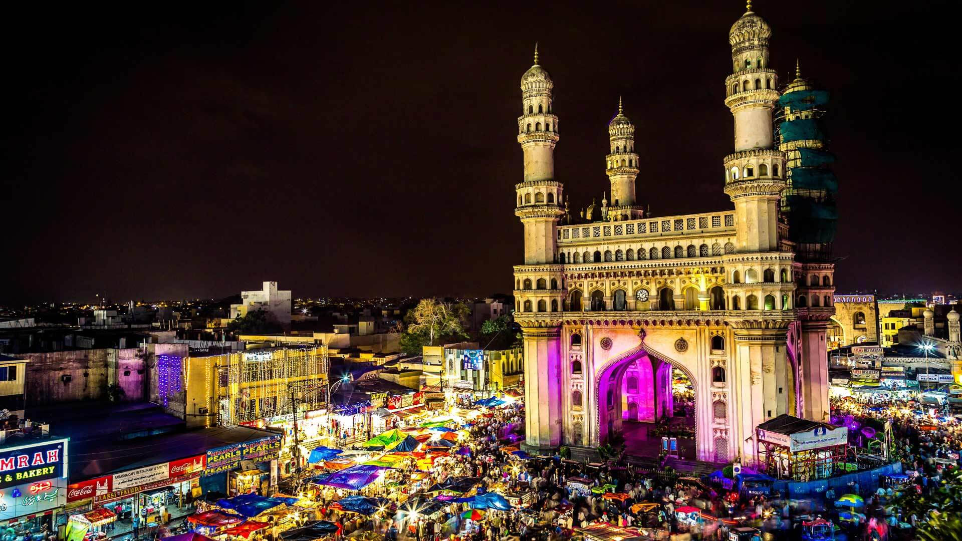 Hyderabad 桌布 壁紙 — 海德拉巴查爾米納爾的充滿活力的夜景，閃爍著五彩燈光，下方人潮湧動。