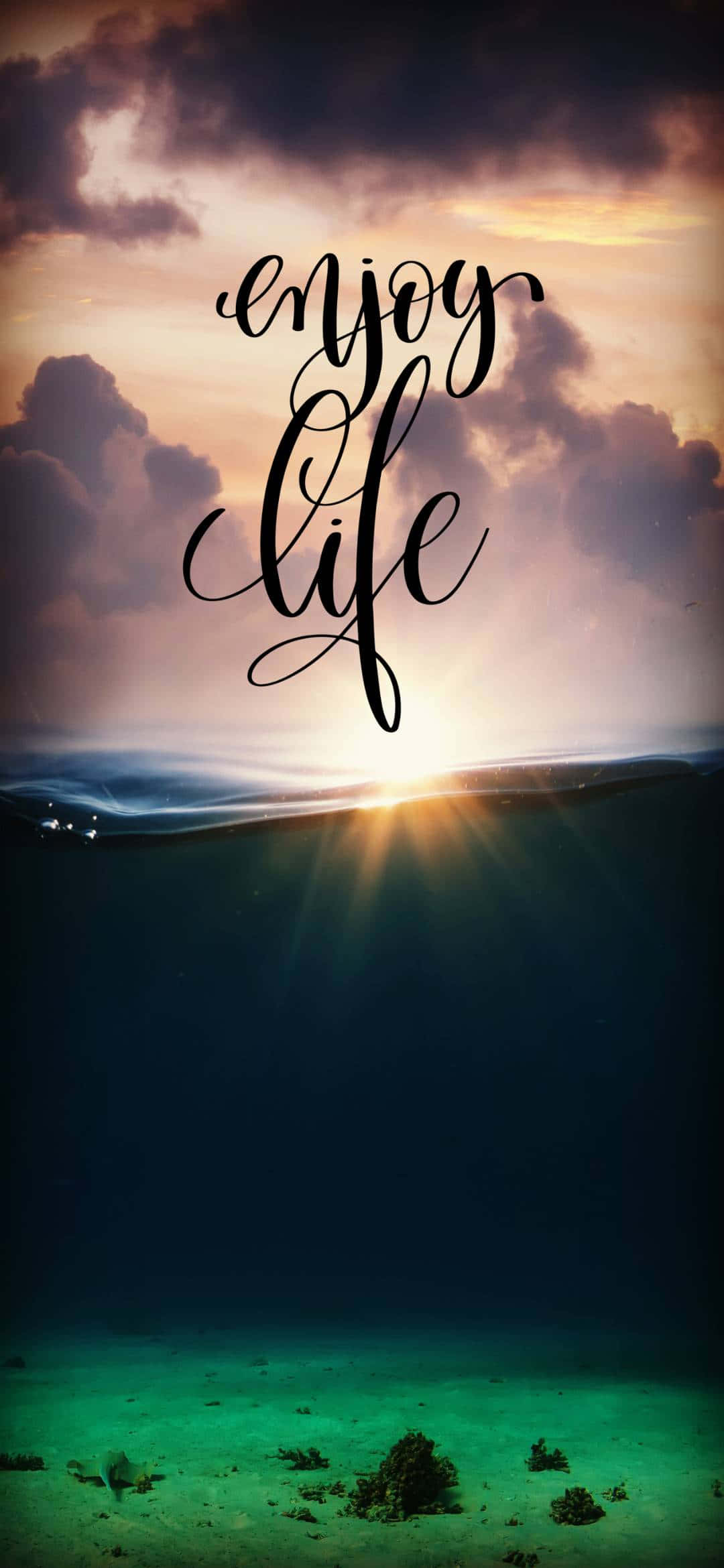 Life Aesthetic 桌布 壁紙 — 海洋上的日落，'enjoy life' 文字漂浮在水面和下方的珊瑚礁之上。