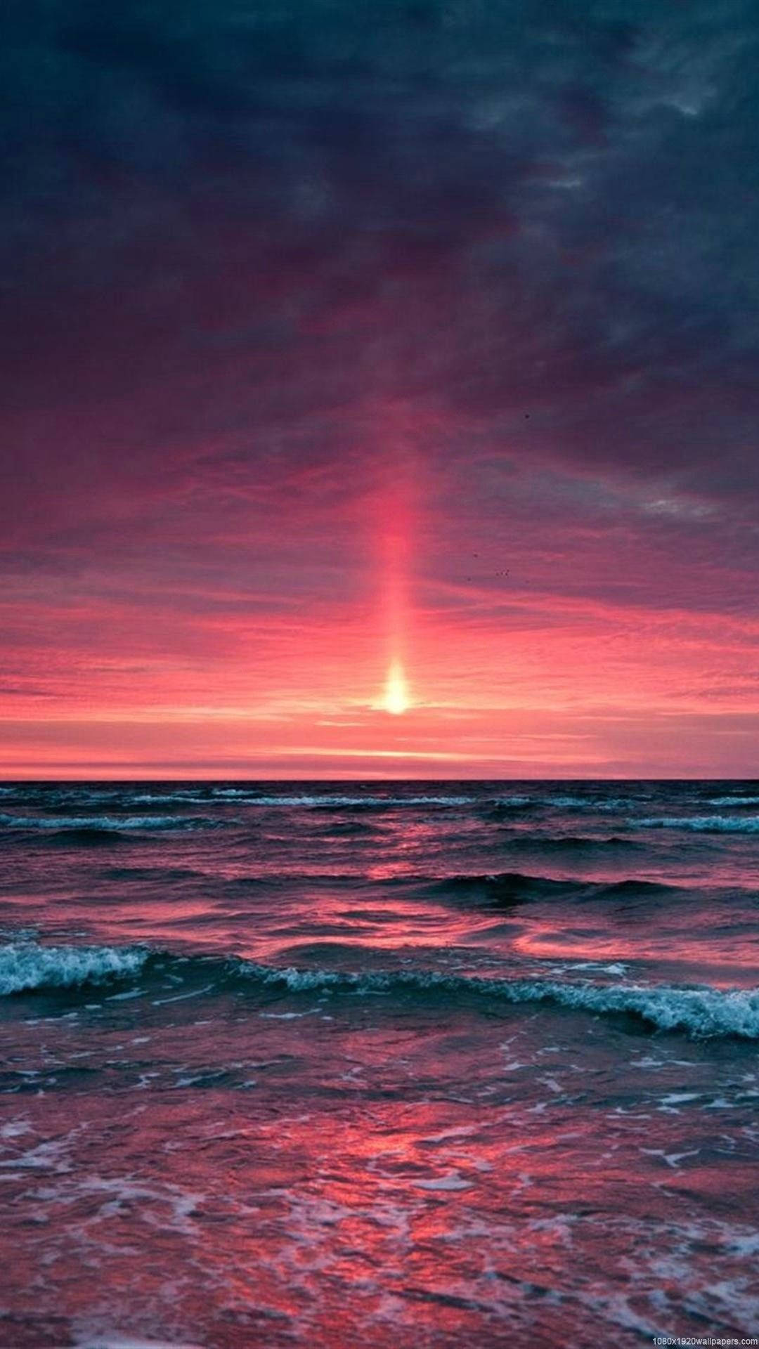 HD nature phone 桌布 壁紙 — 海洋上空戲劇性的日落，燦爛的陽光在天空和水面上投射出火紅和紫色的色調。