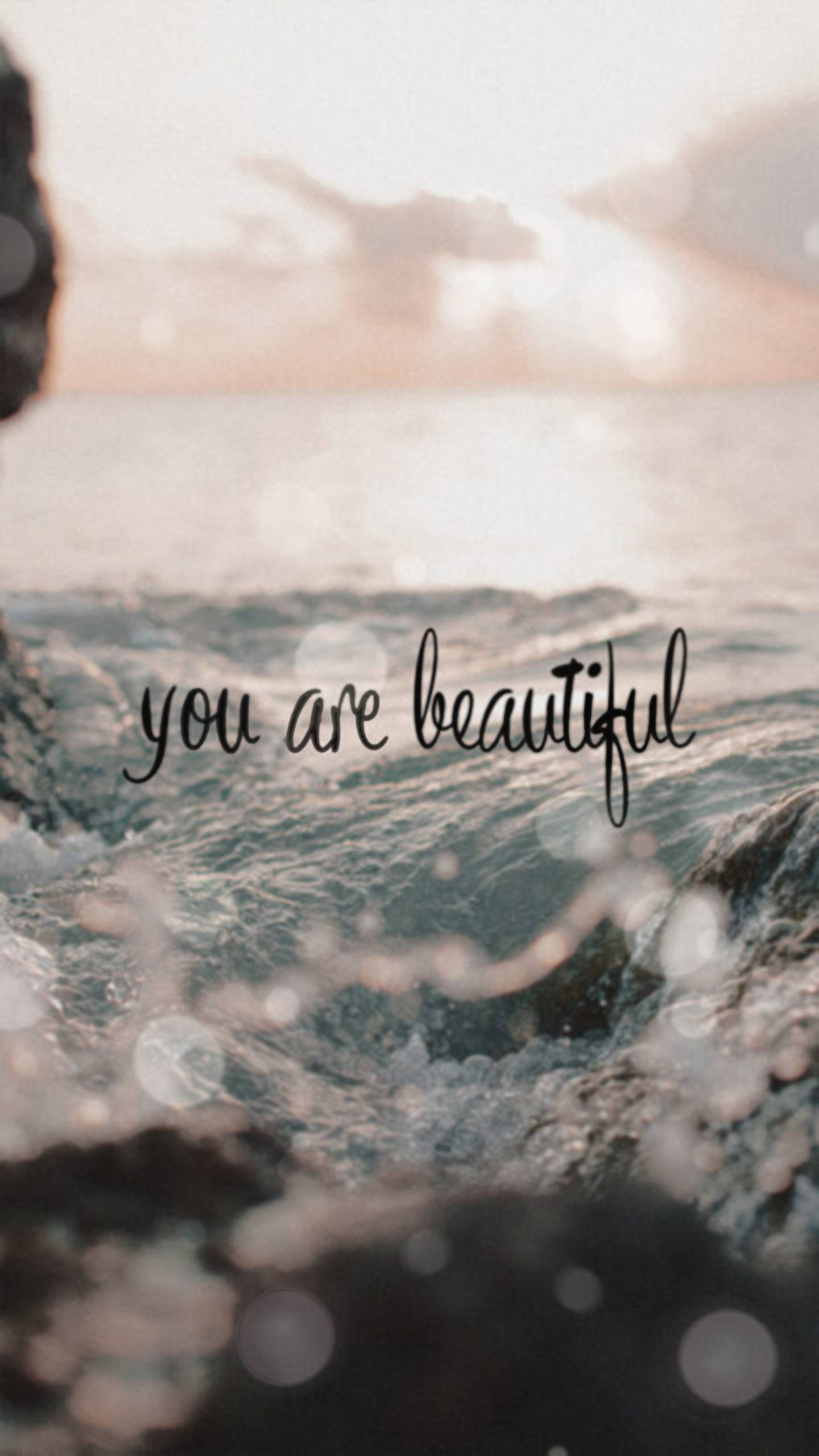 You Are Beautiful 桌布 壁紙 — 海浪在日落時拍打岩石，並疊加了手寫短語「你很美麗」。